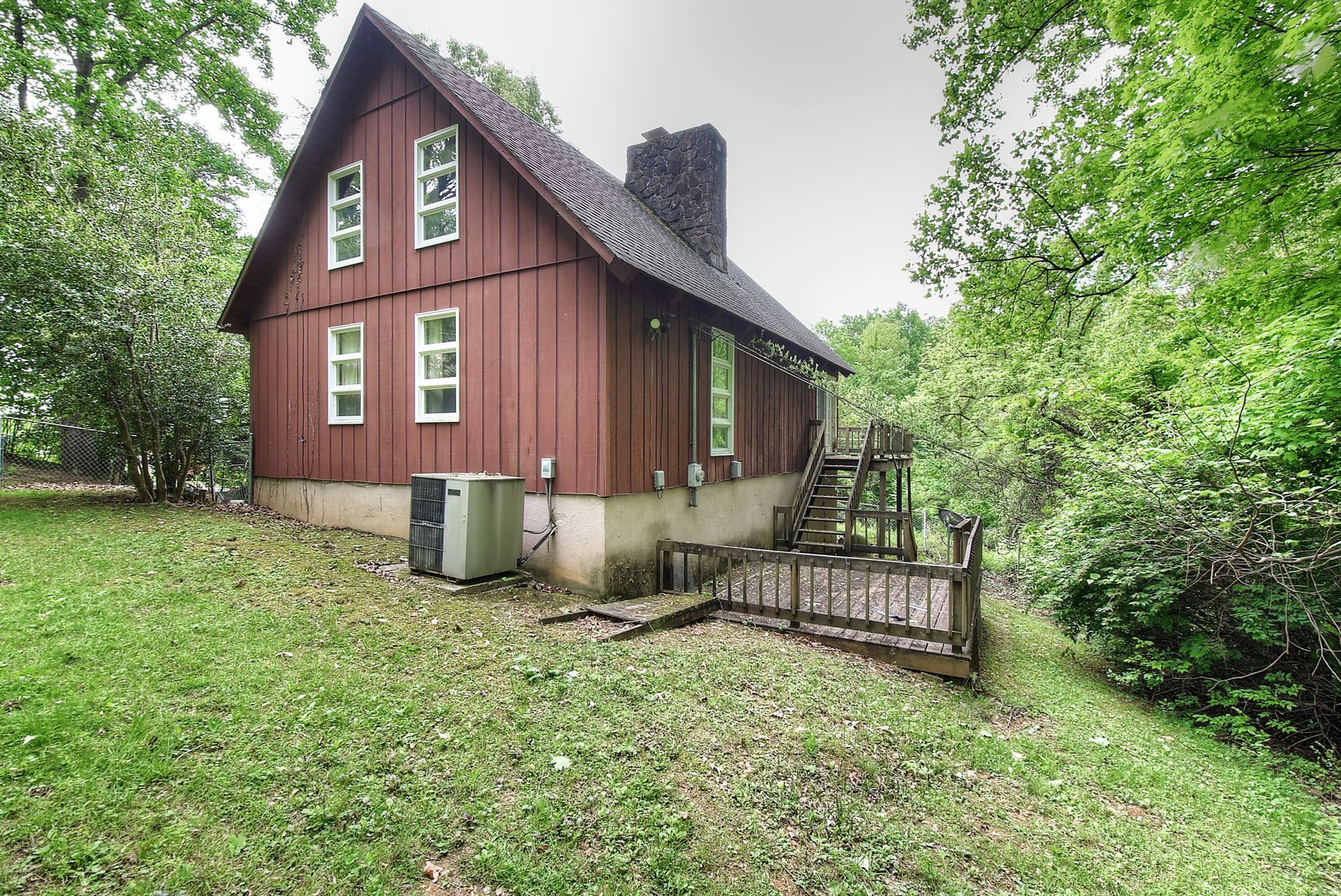 A red barn is sitting on top of a lush green hillside surrounded by trees.