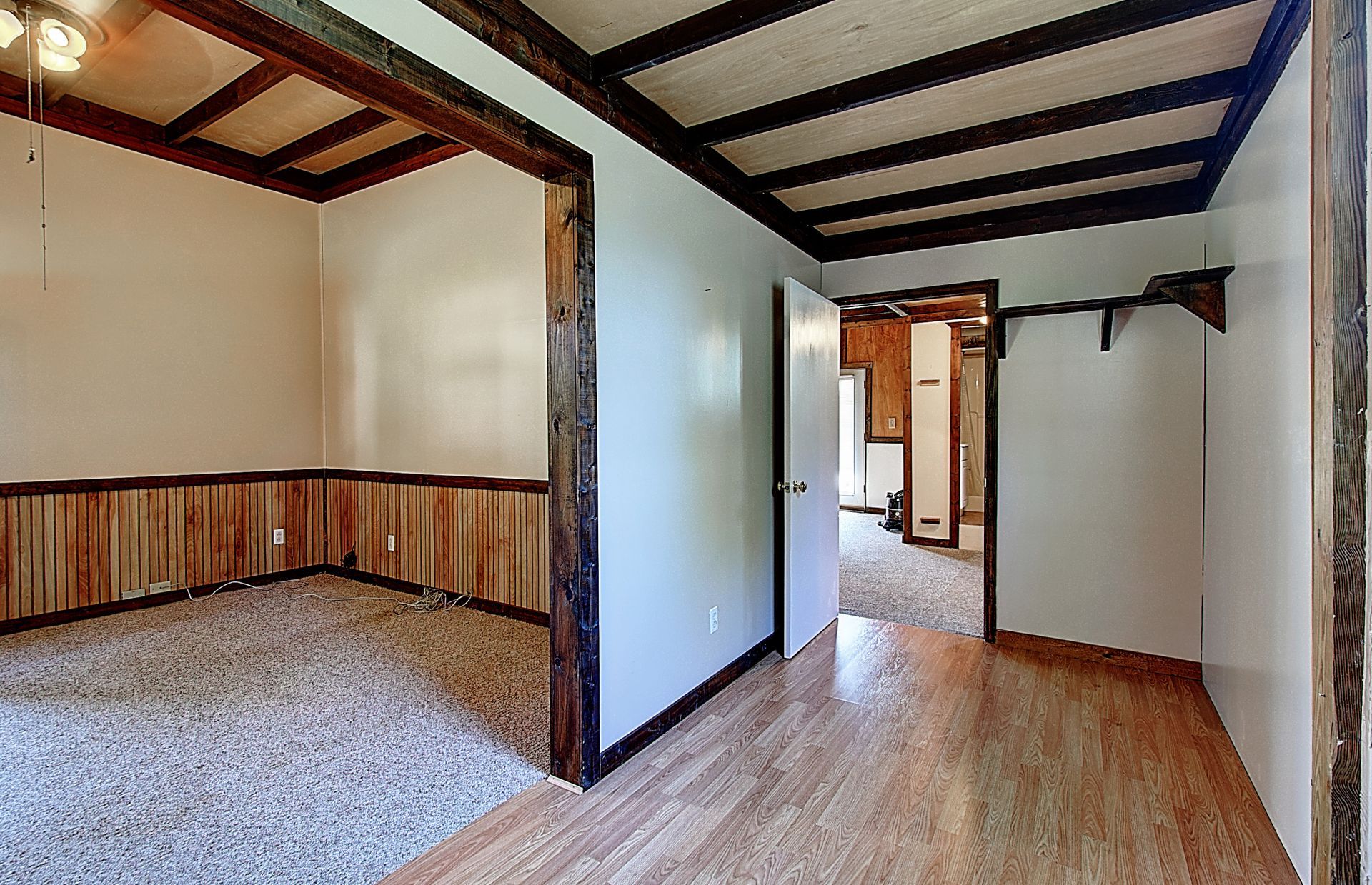 An empty room with wood paneling and hardwood floors