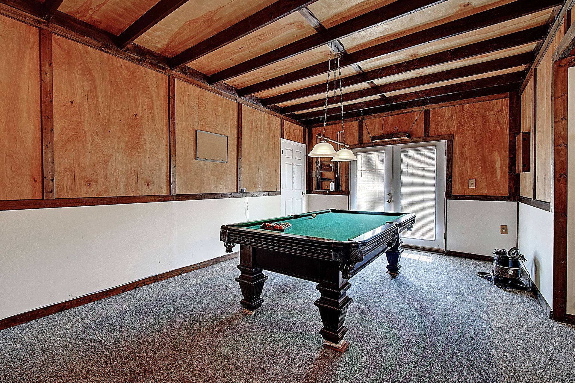 A pool table in a room with a wooden ceiling