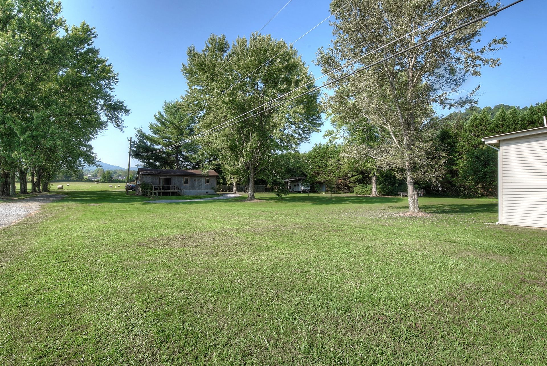 A large lush green field with trees and a house in the background.