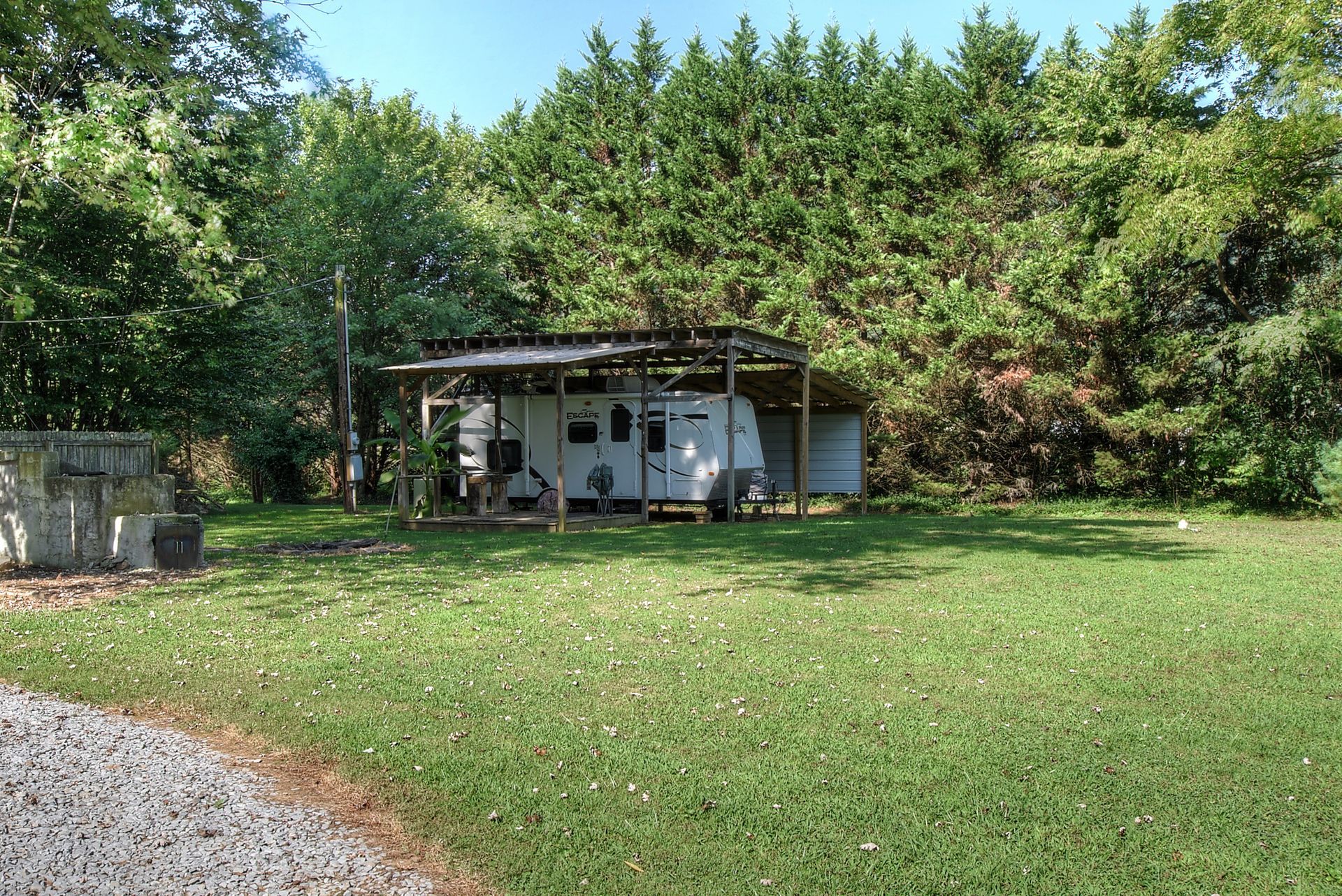 A rv is parked in a grassy field with trees in the background.