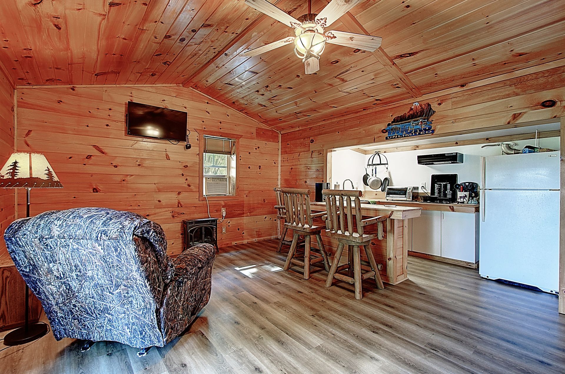 A living room in a log cabin with a chair and a ceiling fan.