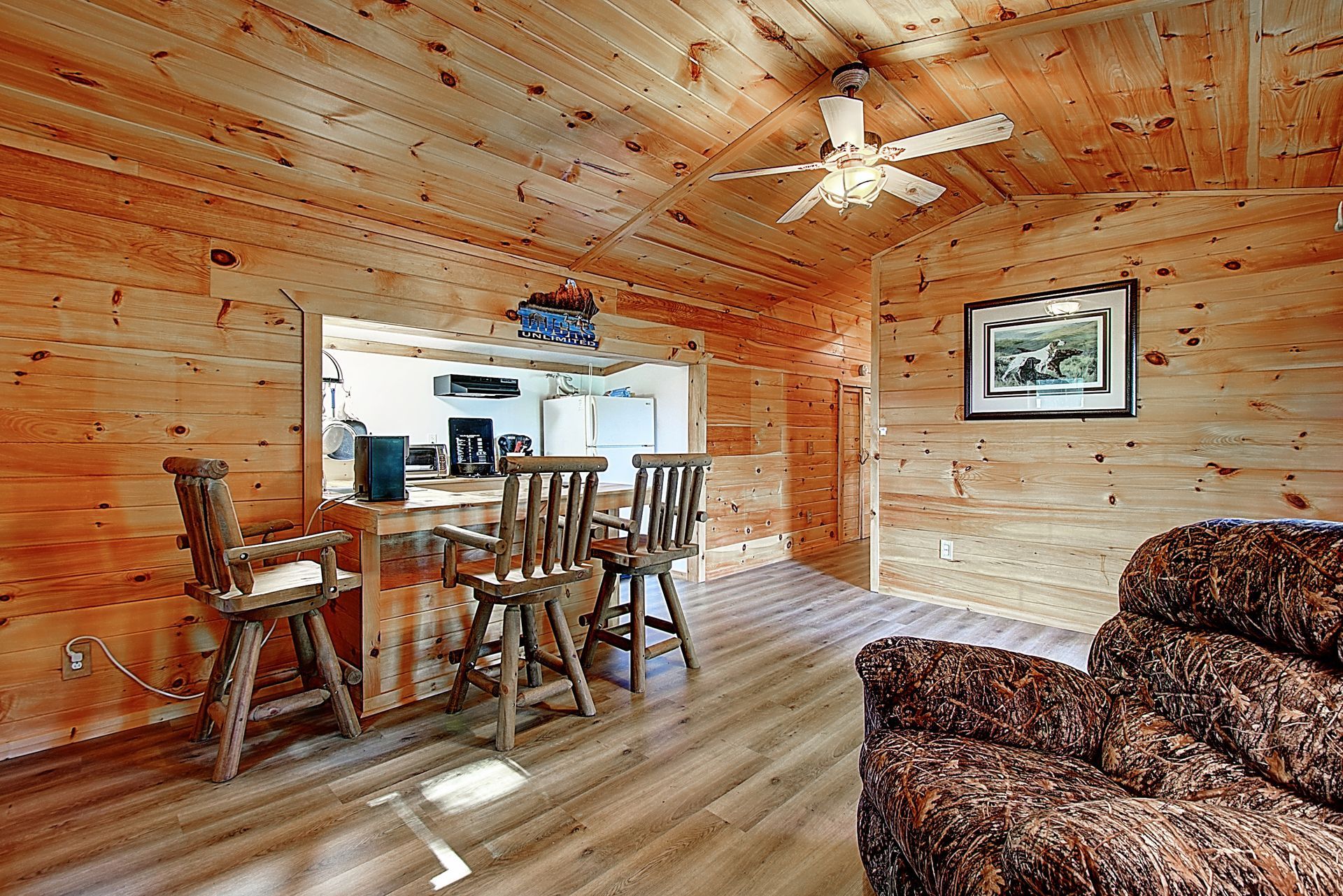 A living room with a dining table and chairs and a ceiling fan.
