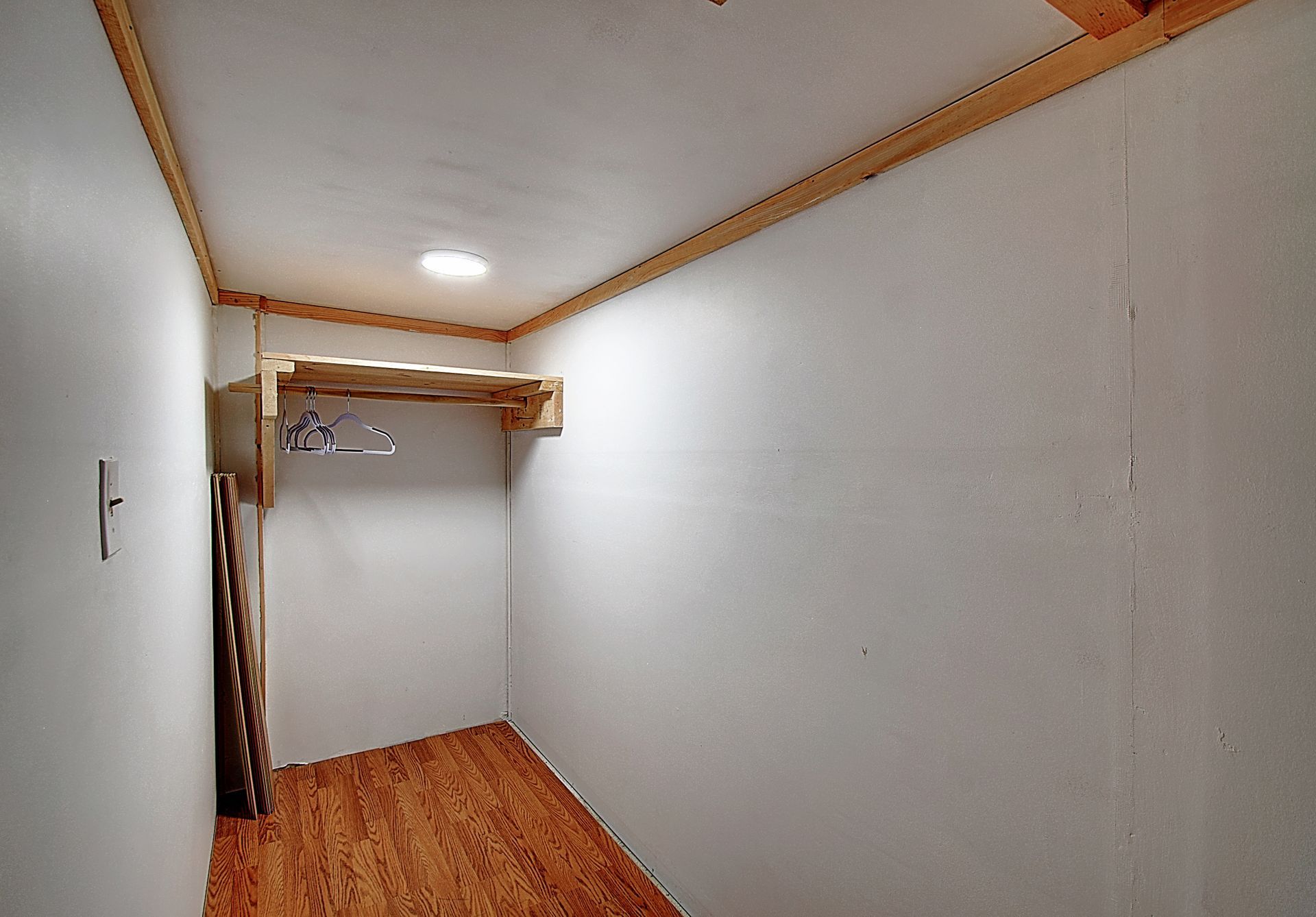 A walk in closet with wooden floors and white walls