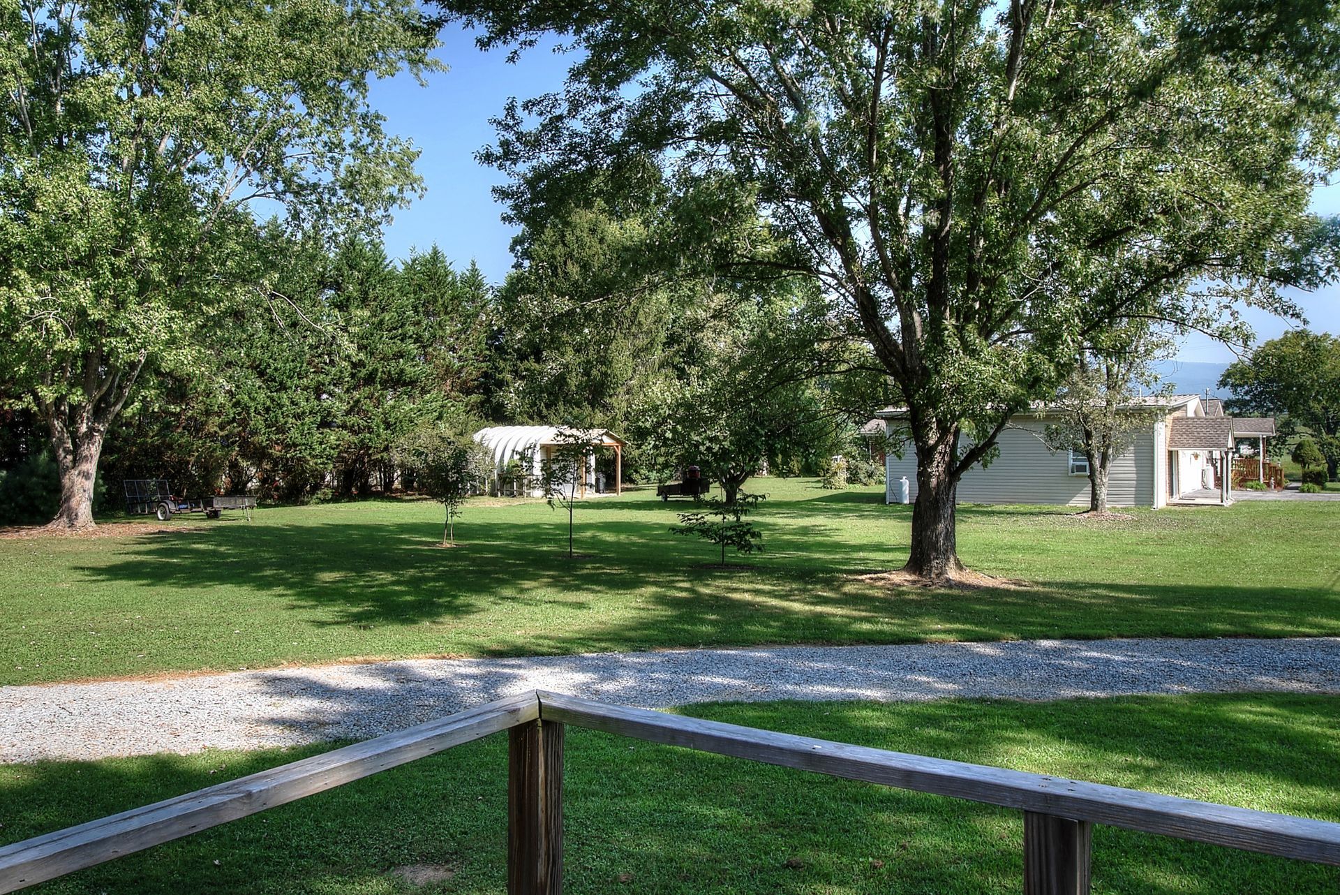 A fence surrounds a lush green field with a house in the background.