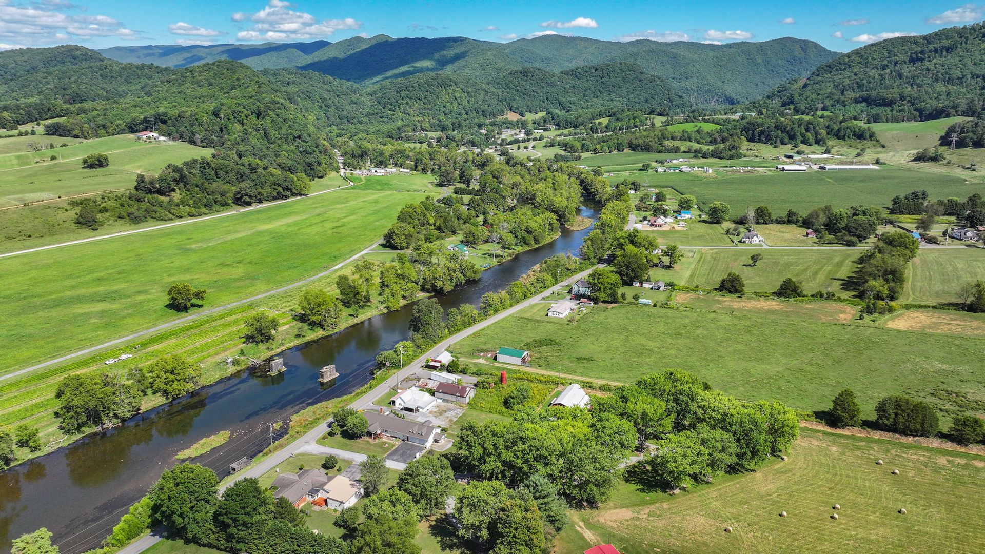 An aerial view of a river running through a lush green field with mountains in the background at 238 Wilbur Dam Rd Elizabethton Tennessee.