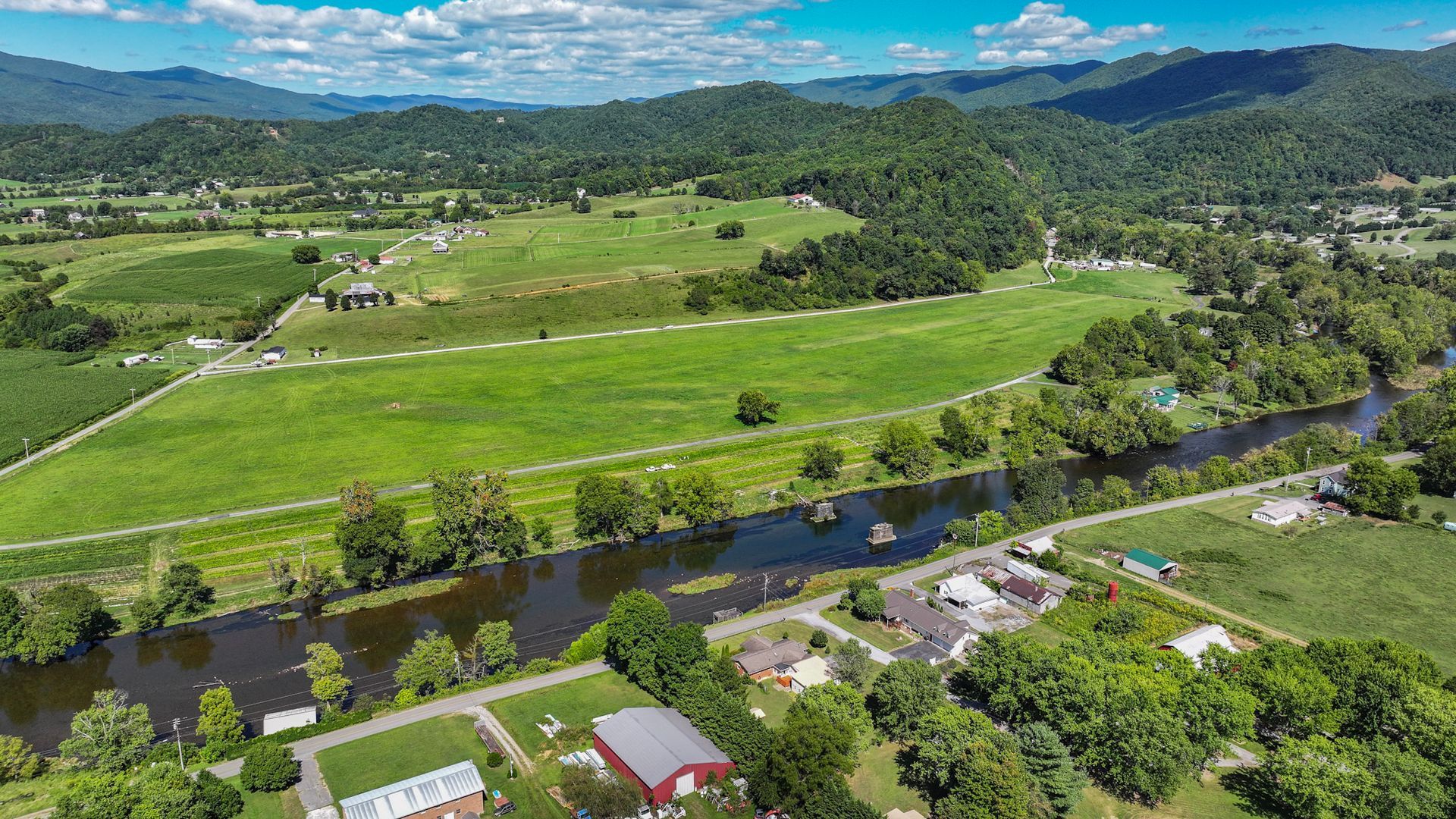 An aerial view of a river running through a lush green field with mountains in the background at 238 Wilbur Dam Rd Elizabethton Tennessee