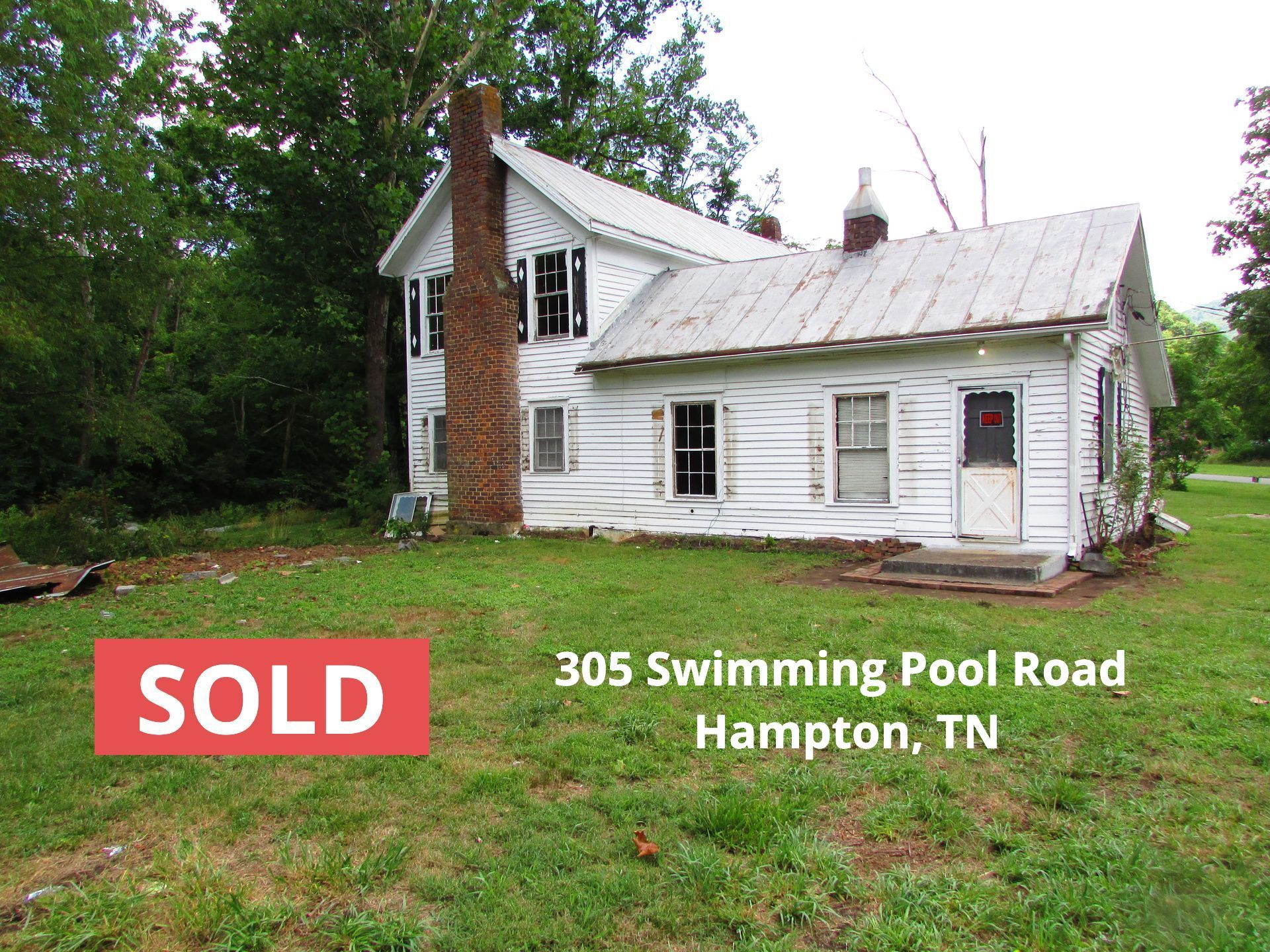 A white house is sitting in the middle of a lush green field.