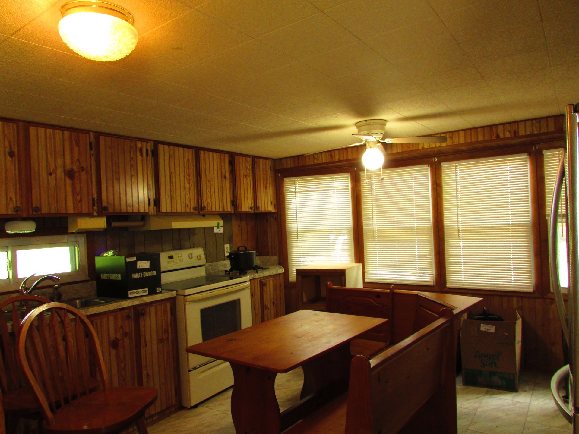 Small kitchen with wood cabinets, a dining table, and bright windows with blinds.