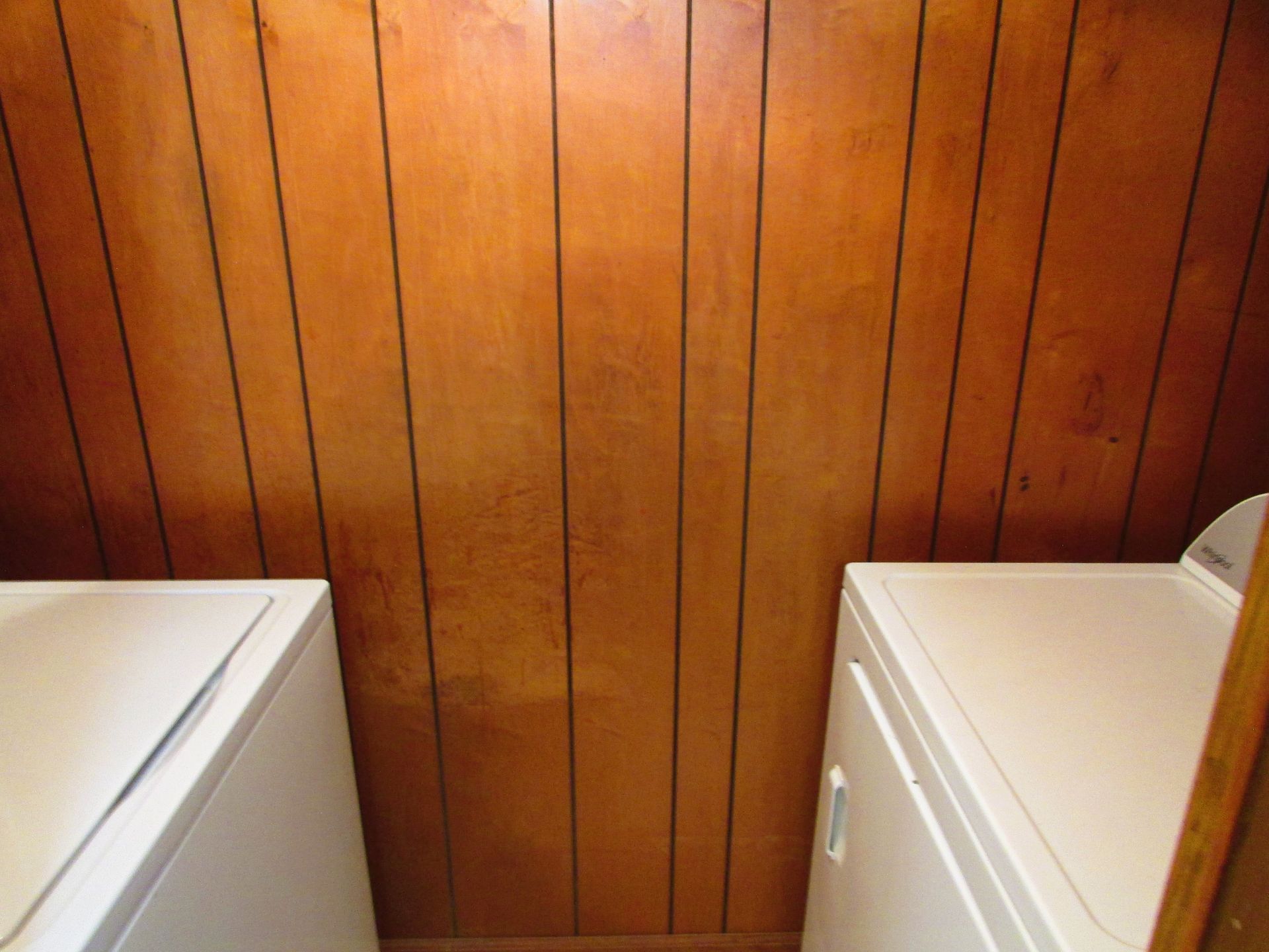 Wood-paneled wall between two white laundry appliances