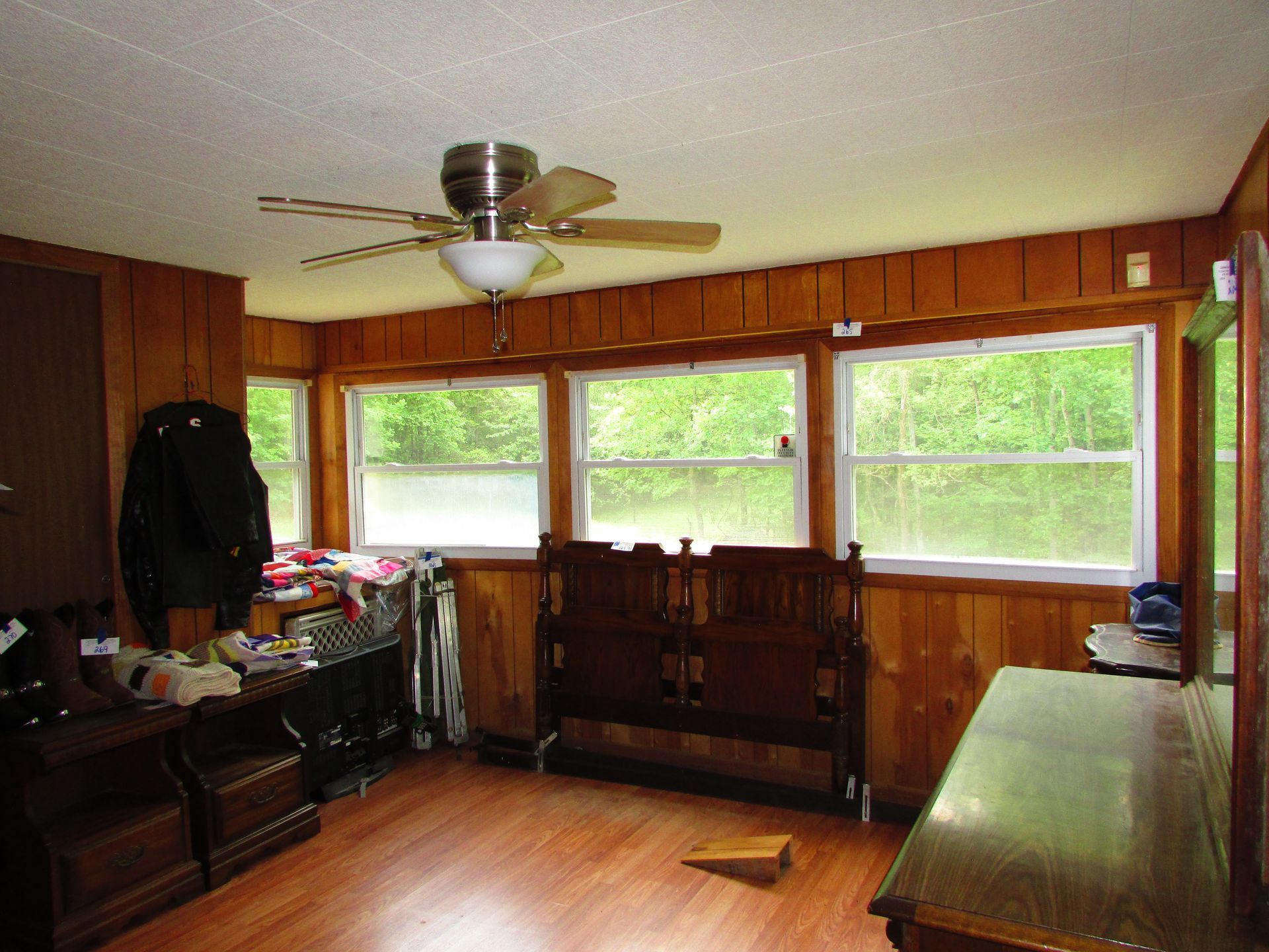 Wood-paneled sunroom with large windows, ceiling fan, and hardwood floor