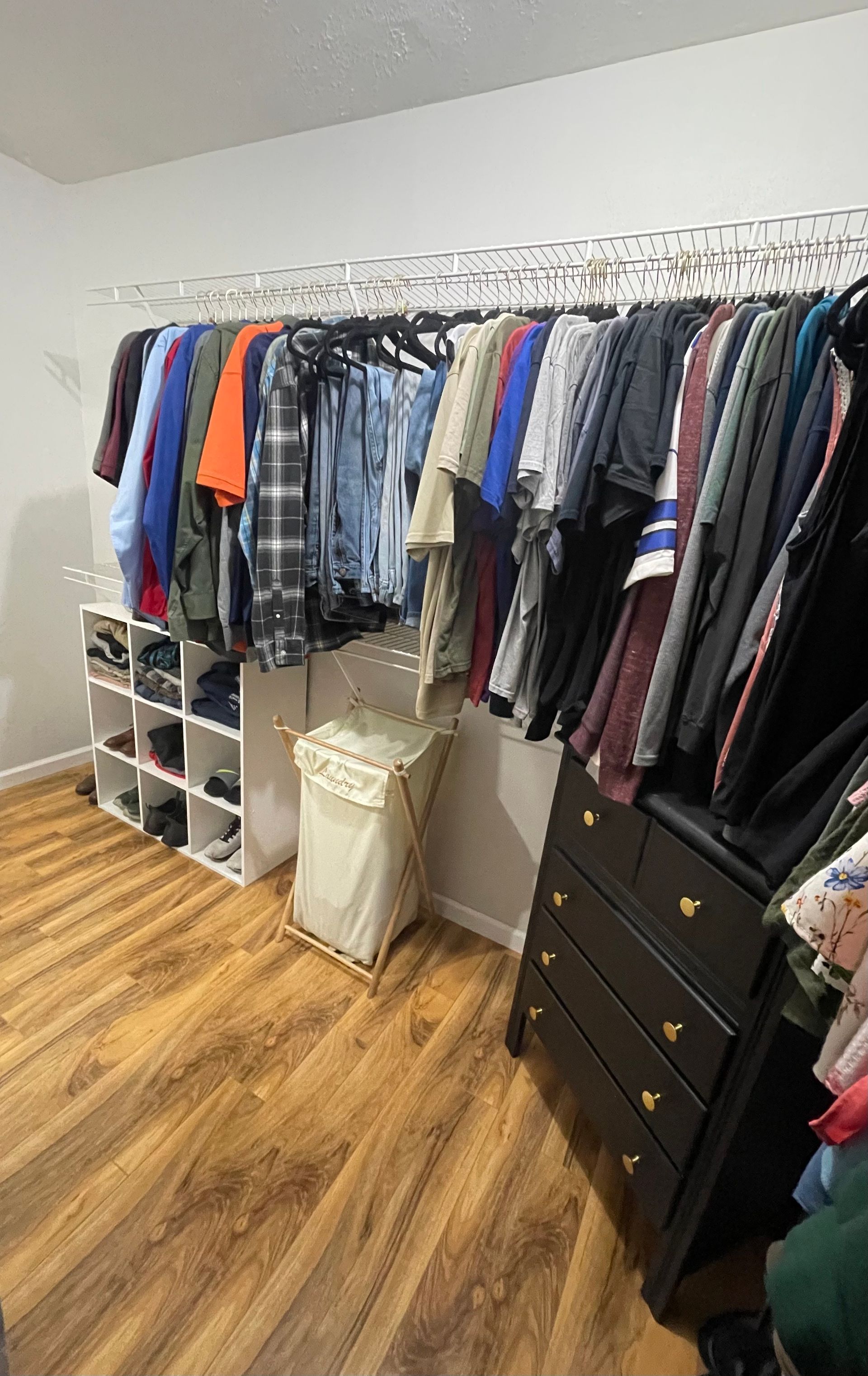 A walk in closet filled with lots of clothes and a laundry basket.