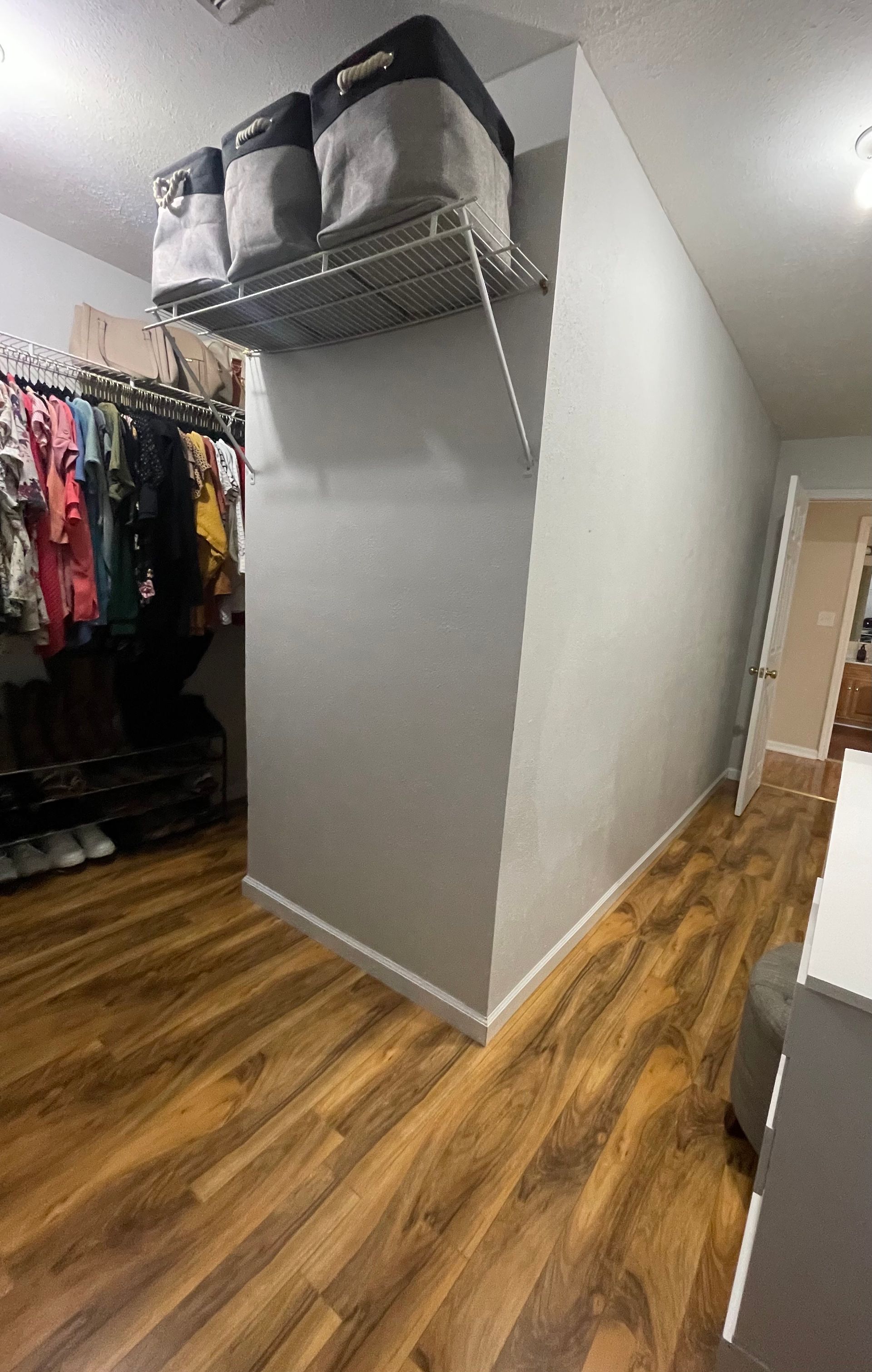 A hallway with hardwood floors and a shelf hanging from the wall.