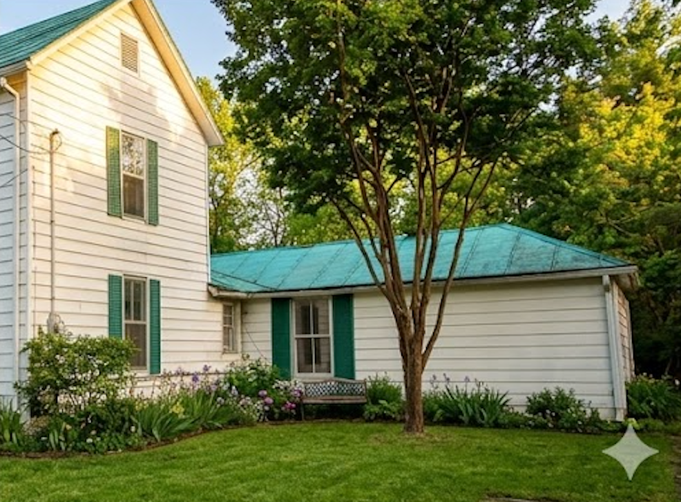 White house with green shutters and roof, tree in front, sunny day.