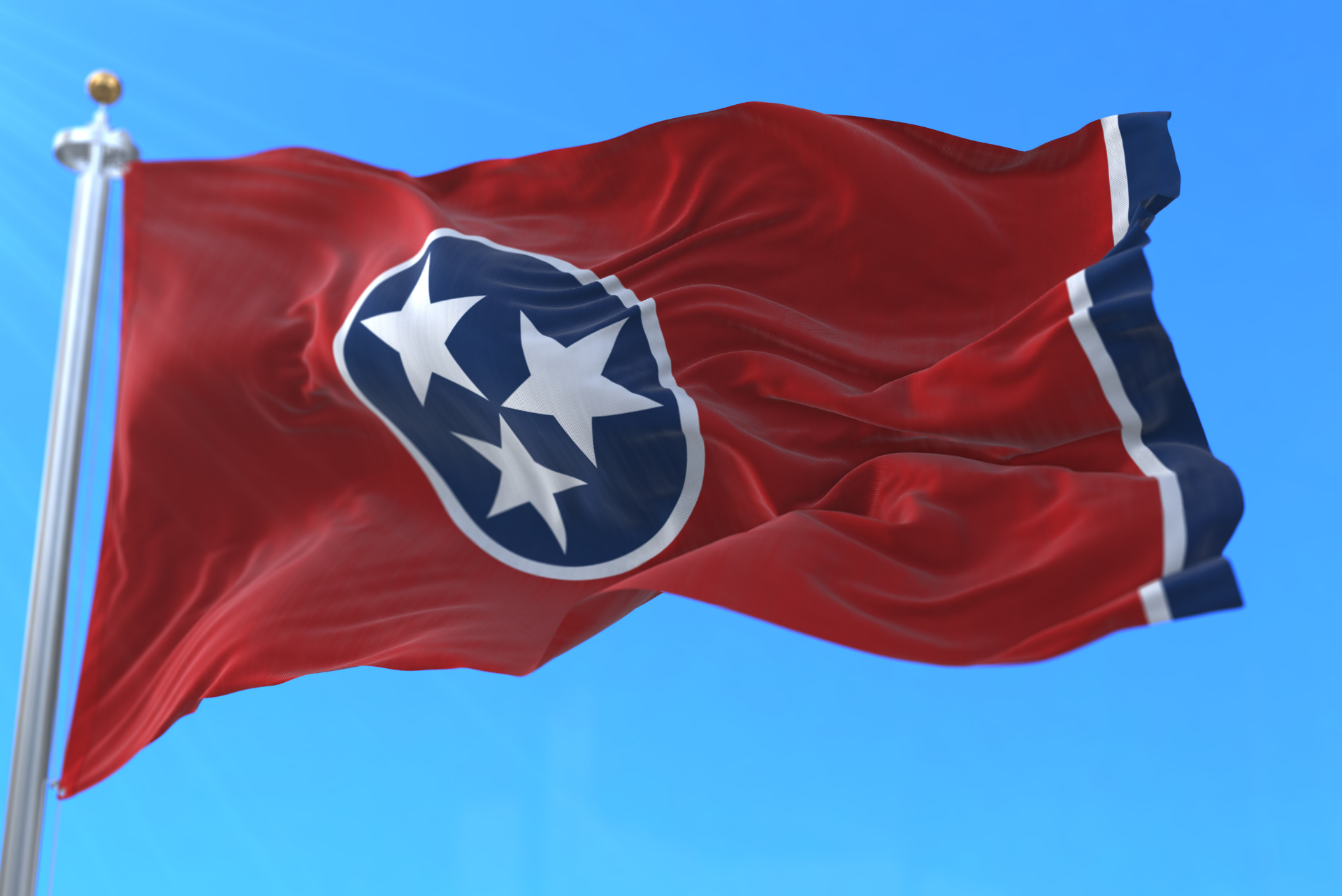 Tennessee state flag waving against a blue sky