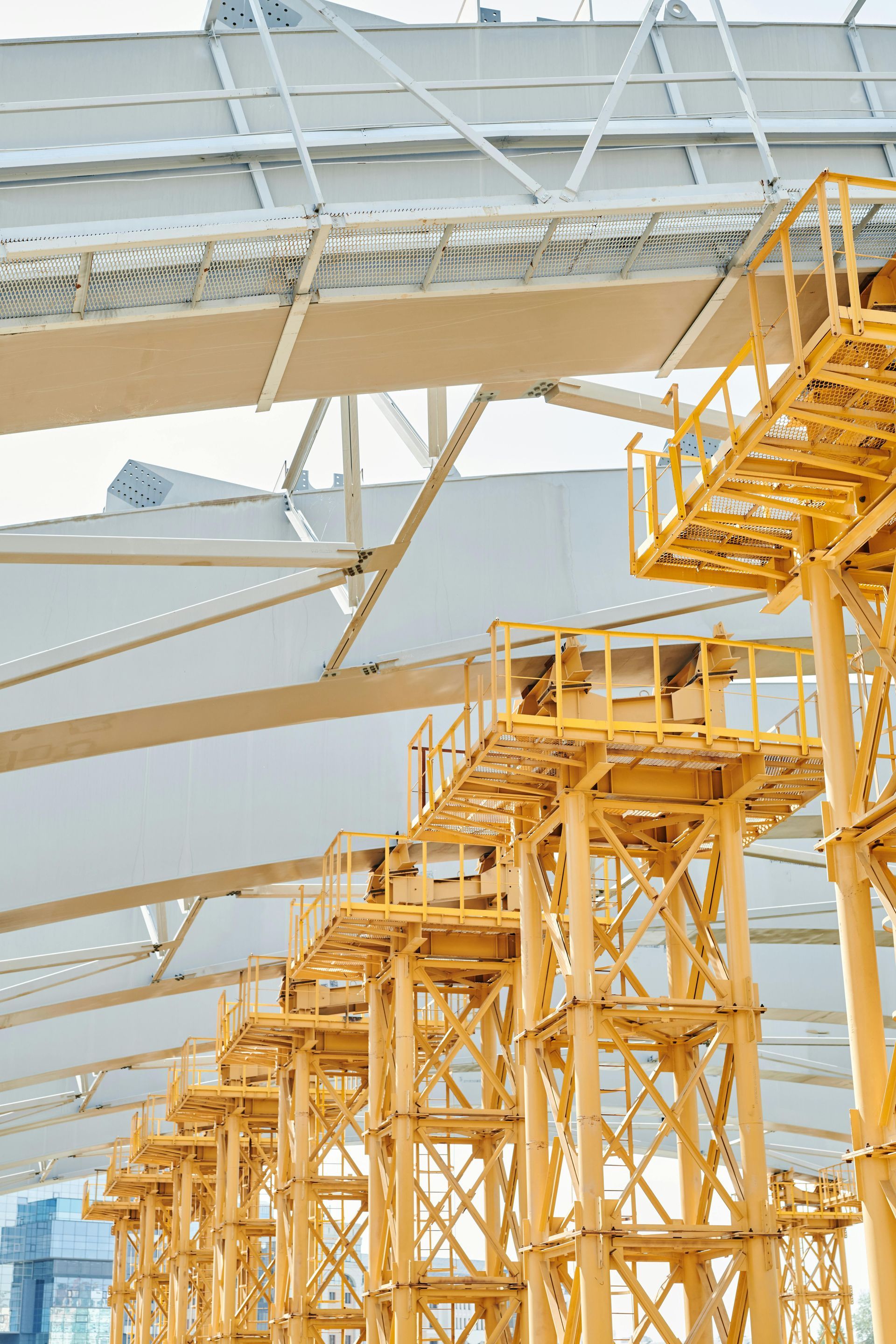 Yellow scaffolding supports a white roof structure under a bright sky.