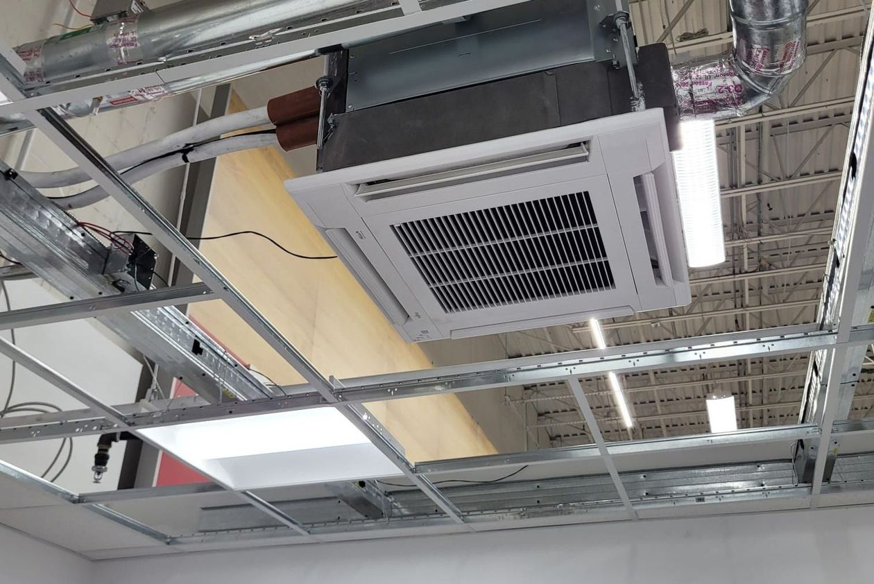 Ceiling-mounted HVAC unit installed in a commercial space. Ductwork and lights are also visible.