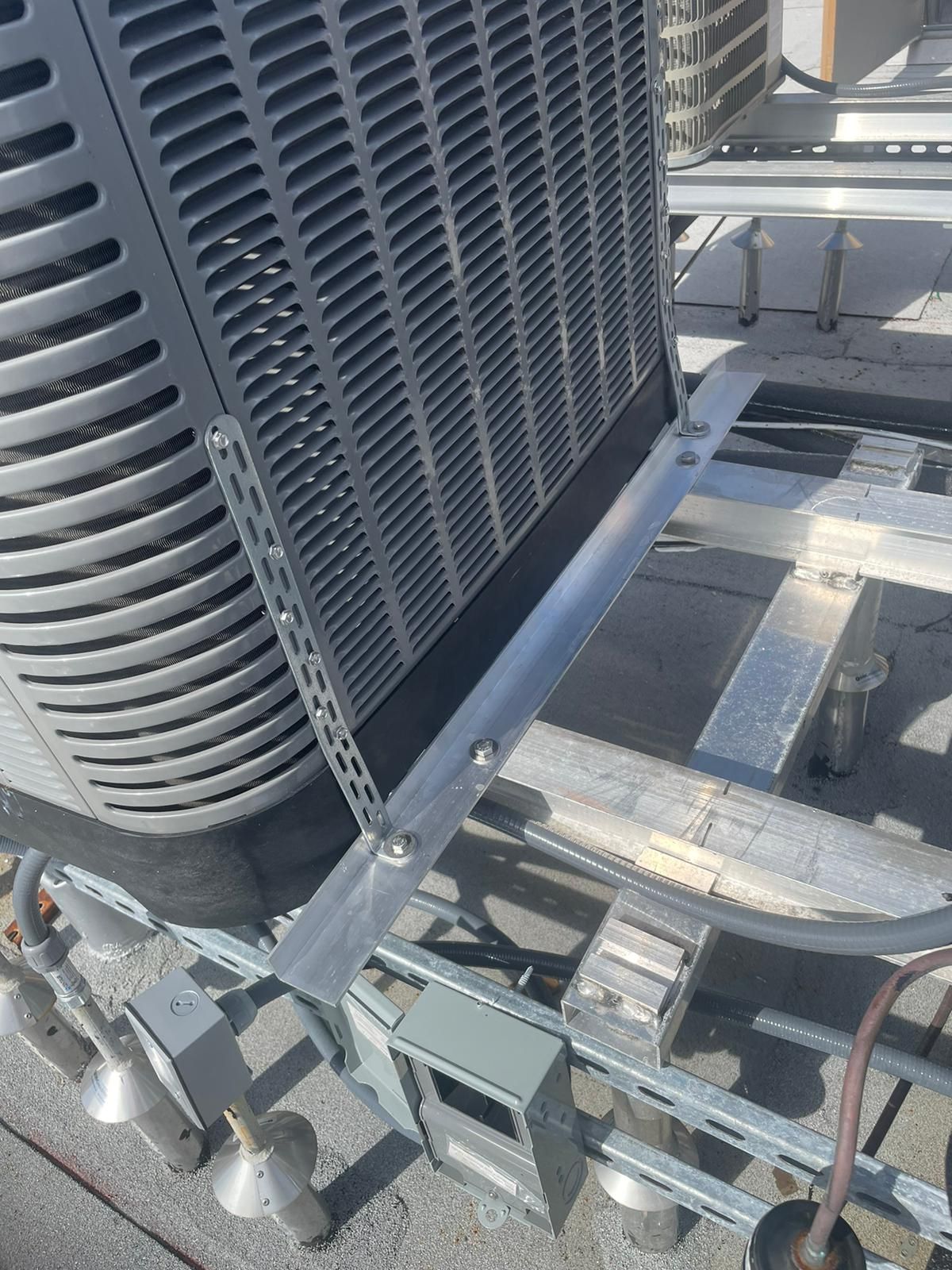 HVAC unit on a rooftop platform, with metal supports and a gray exterior.