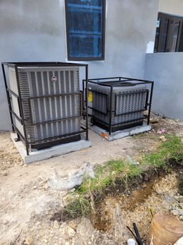 Two outdoor air conditioning units with protective metal cages, near a building.