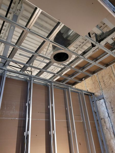 Construction site interior: metal framework for ceiling and walls; exposed ductwork.