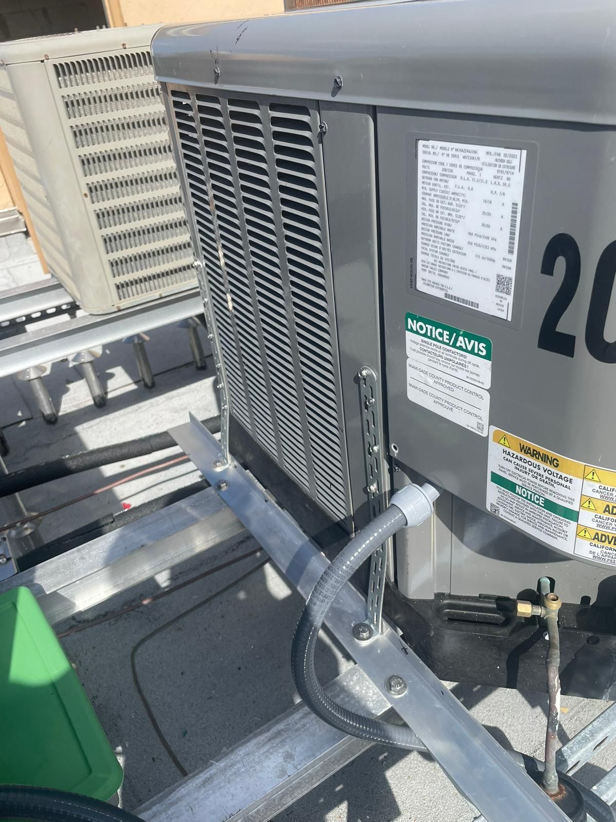 HVAC unit on a rooftop with a side panel and electrical conduit. The unit has the number 20 visible.