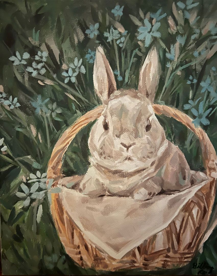 Gray rabbit in a basket, surrounded by green foliage and blue flowers.