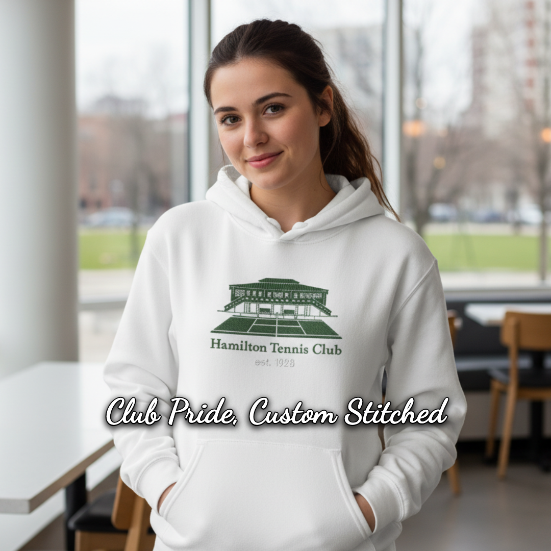 Woman wearing a white hoodie with a Hamilton Tennis Club logo. Indoors, smiling.