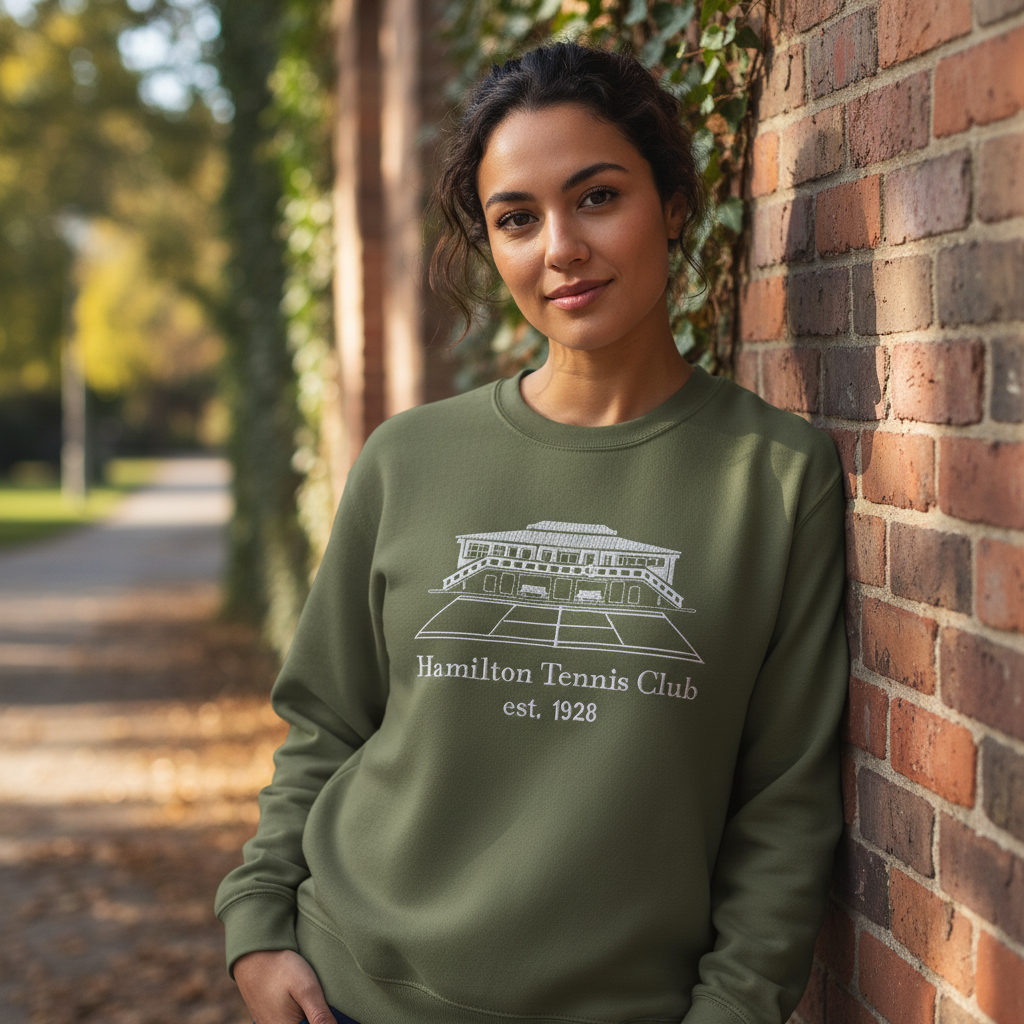 Woman wearing green sweatshirt leans against brick wall; 