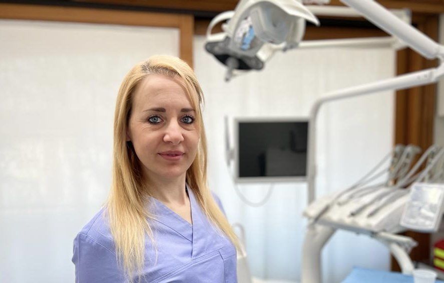 Una donna è in piedi in uno studio dentistico davanti a un apparecchio odontoiatrico.