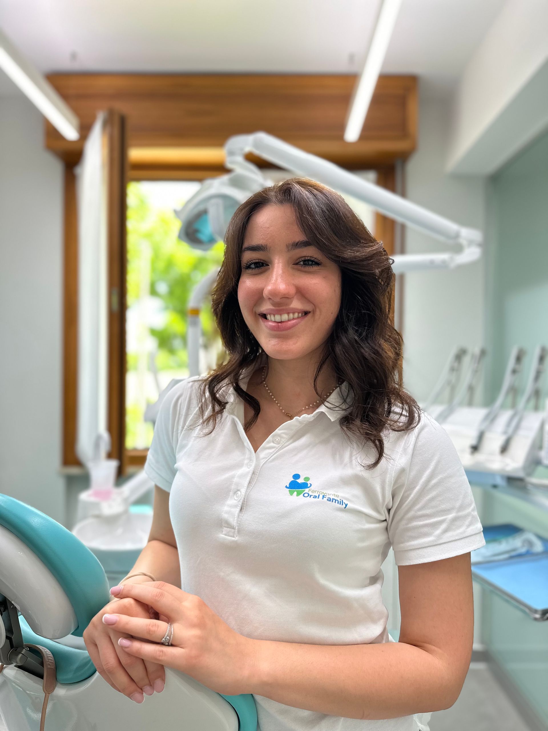 Una donna con una camicia bianca è in piedi in uno studio dentistico.