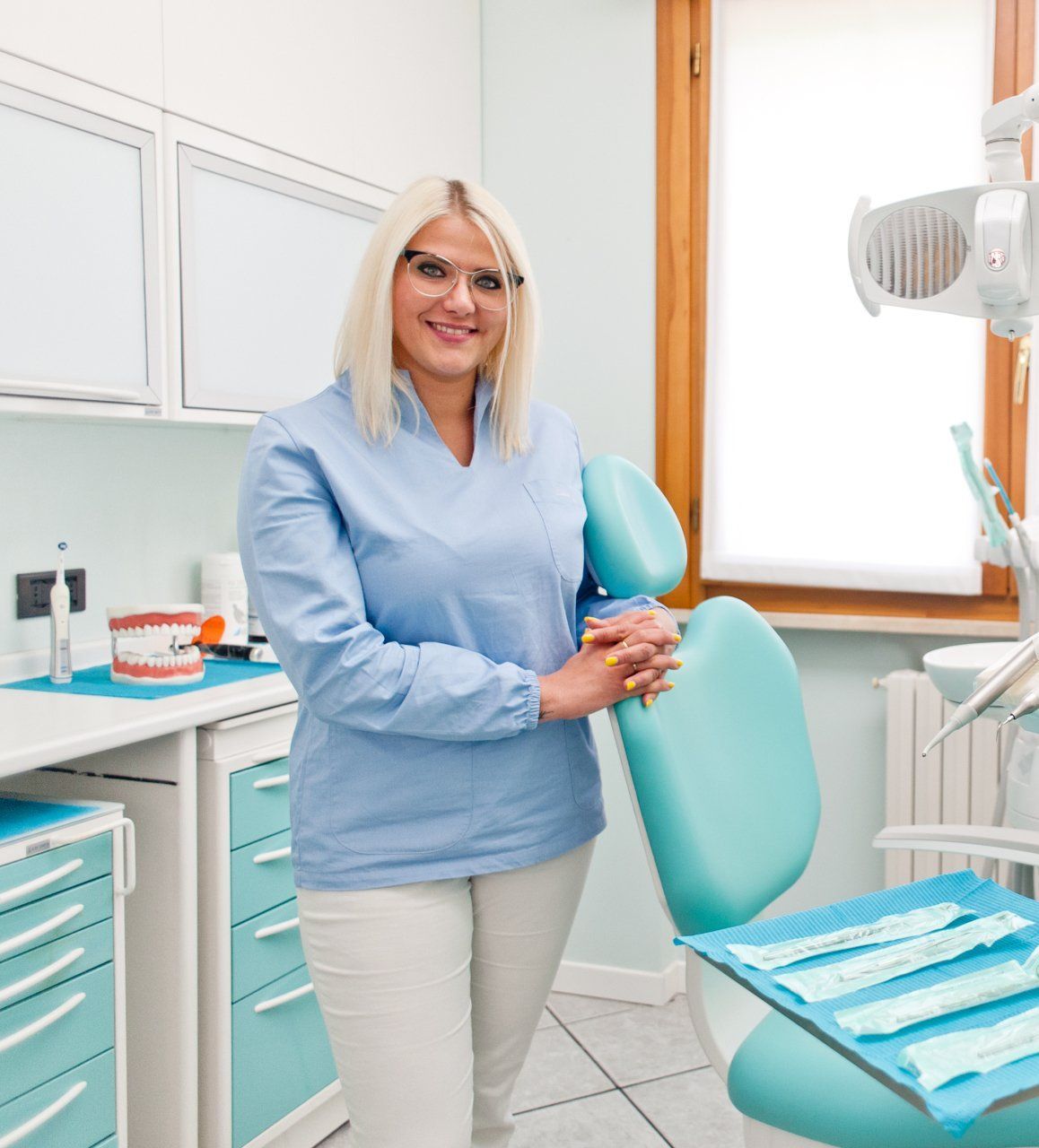 Una donna è in piedi in uno studio dentistico accanto a una poltrona.