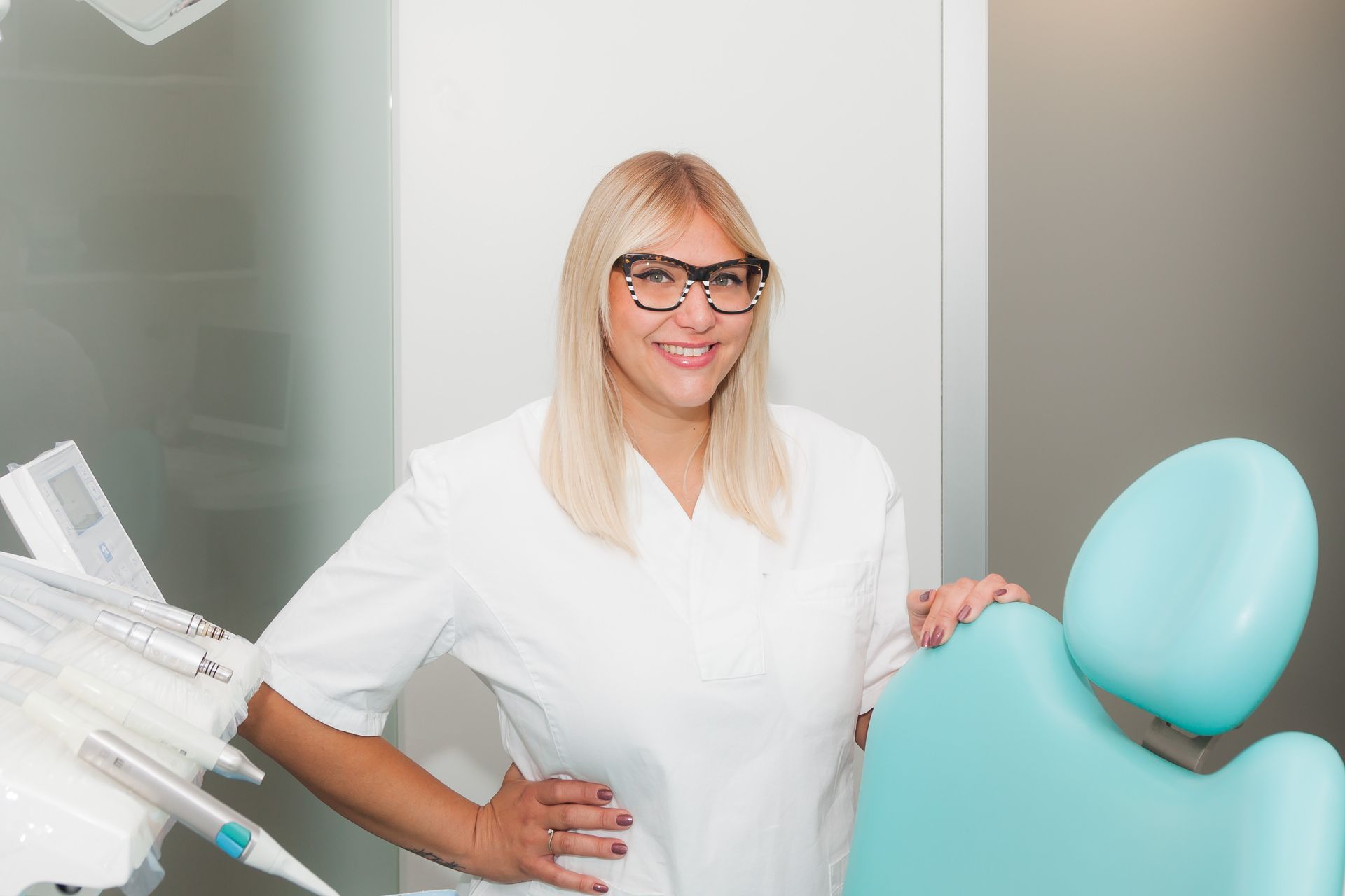 Una donna è in piedi in uno studio dentistico accanto a una poltrona.