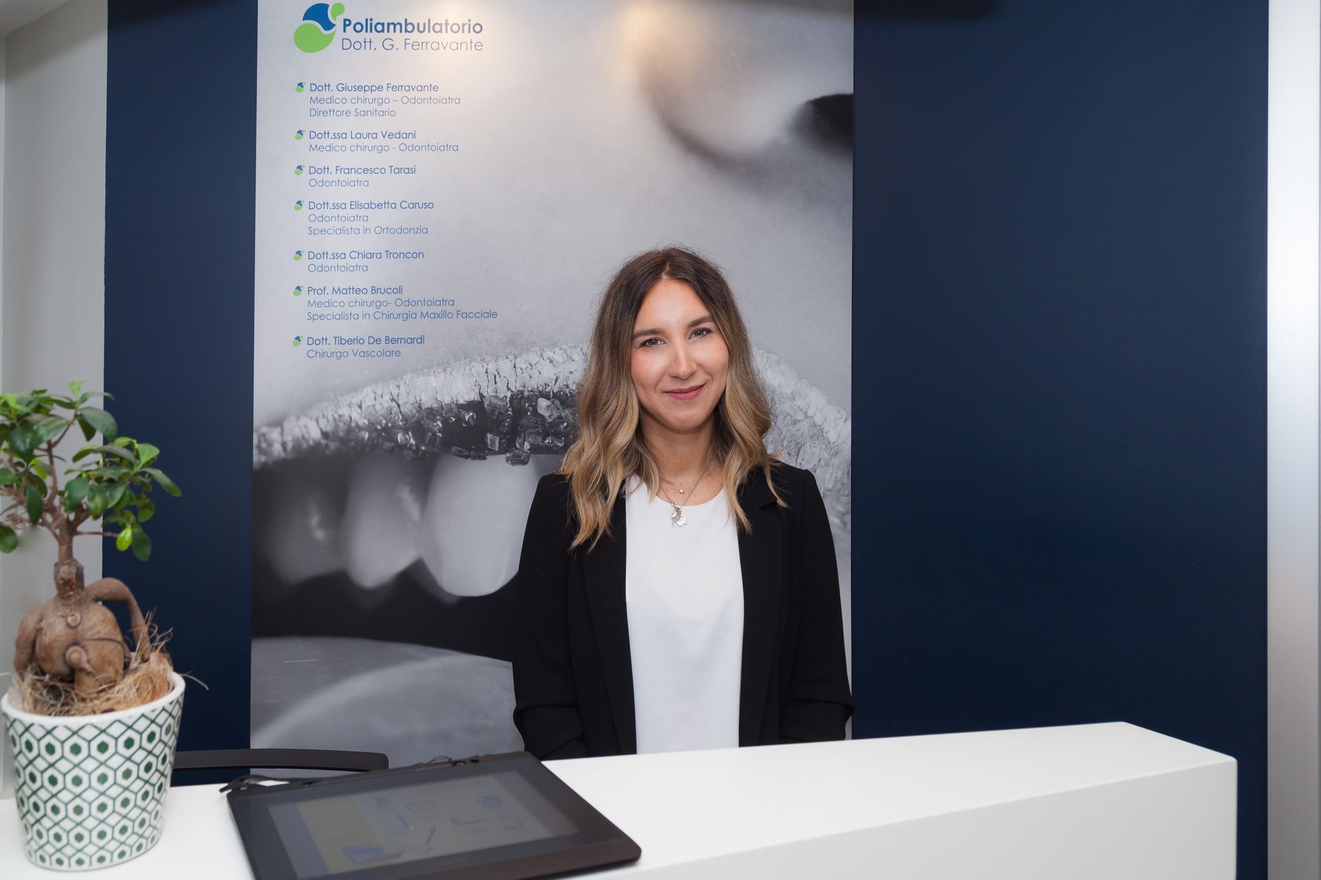 Una donna è in piedi accanto alla poltrona del dentista in uno studio dentistico.