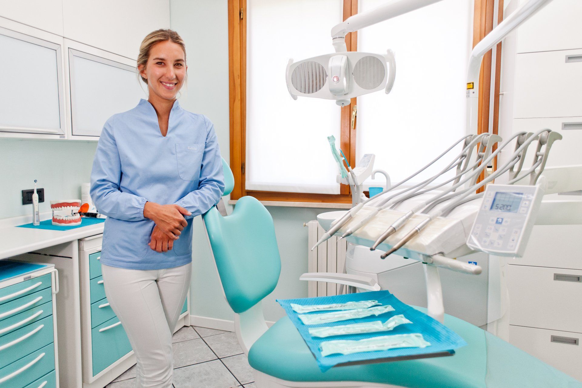 Una donna è in piedi accanto alla poltrona del dentista in uno studio dentistico.