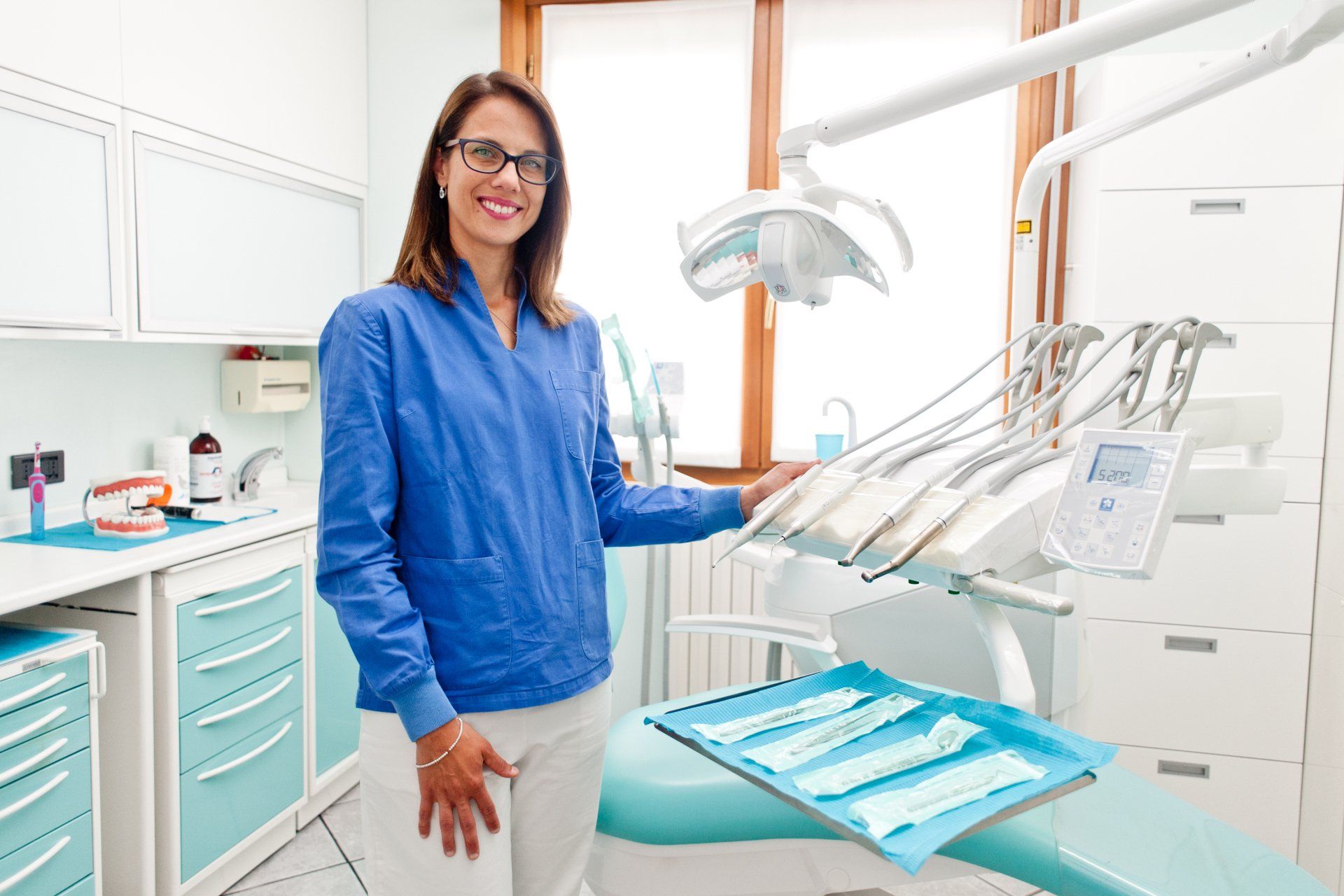 Una donna è in piedi in uno studio dentistico accanto a una poltrona.