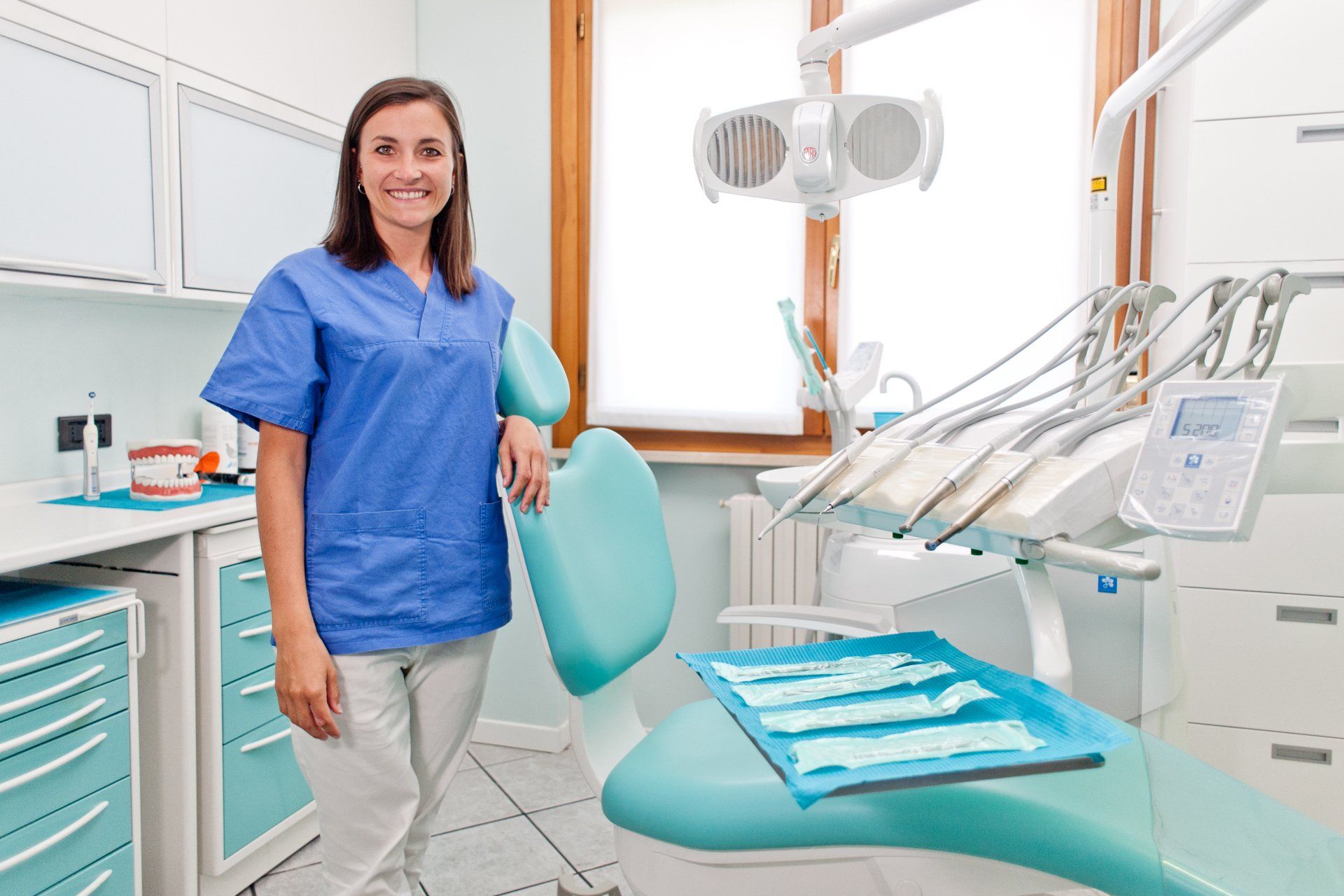 Una dentista è in piedi accanto a una poltrona del dentista in uno studio dentistico.