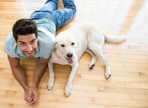 man and a dog laying on a wooden floor