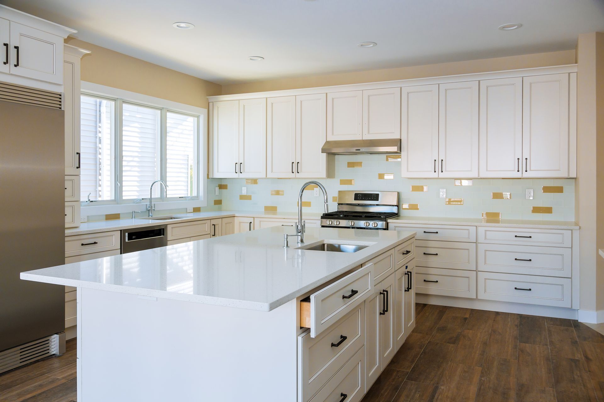 Bright modern kitchen with white cabinets, island, stainless appliances, and wood flooring
