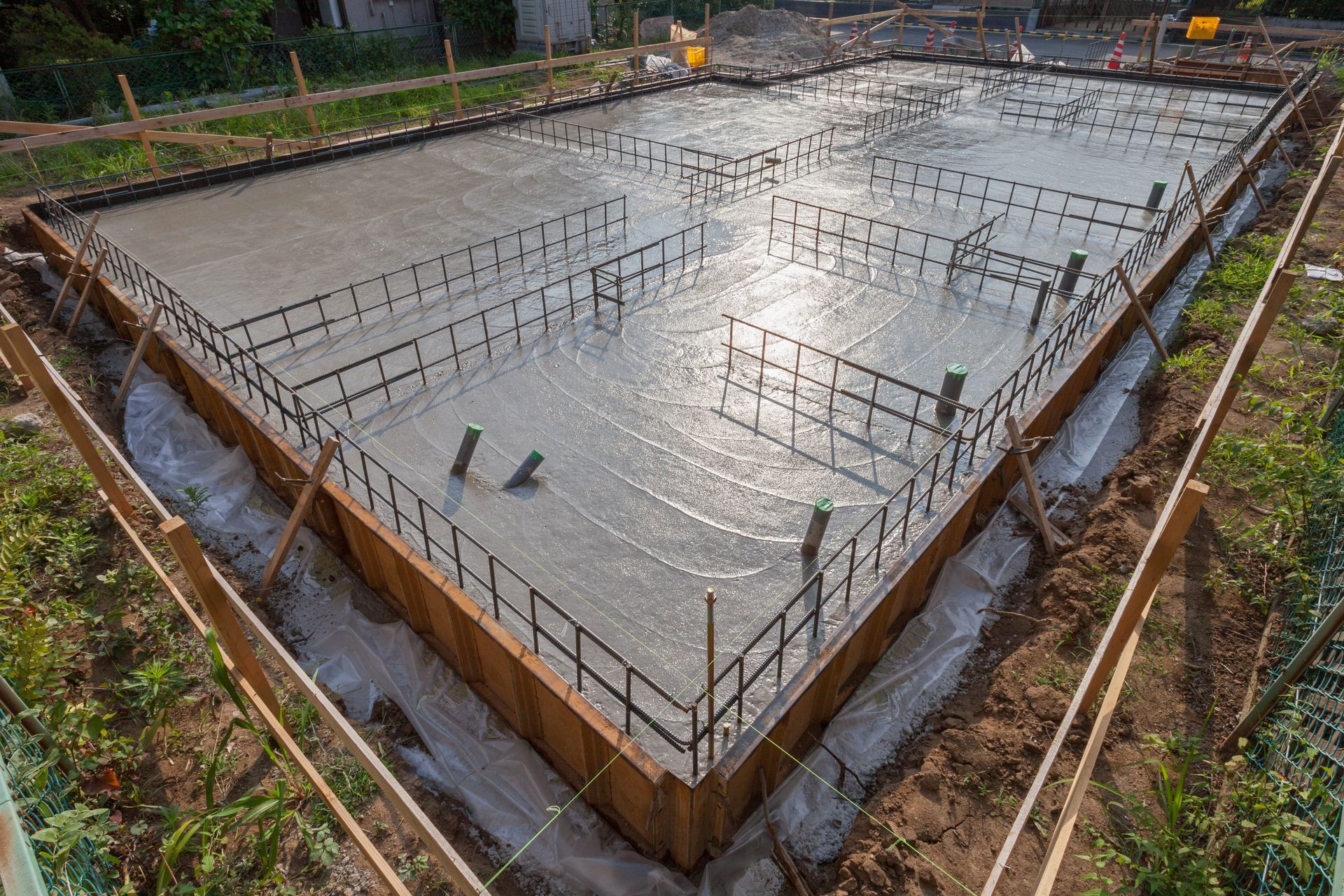 Freshly poured concrete foundation with steel rebar grid at a construction site