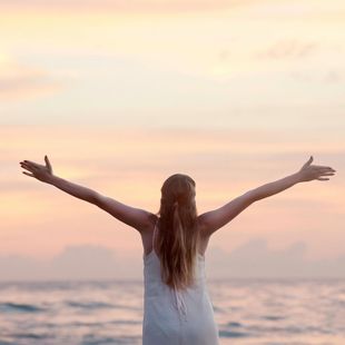 woman facing the sunset with her arms out in joyful expression