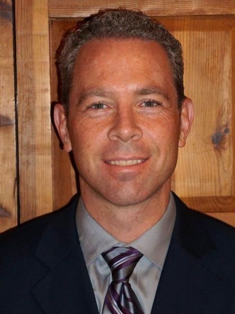 A man in a suit and tie is smiling for the camera