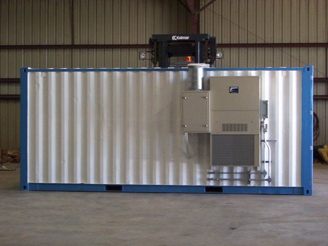 A shipping container with a crane on top of it is sitting in a warehouse.