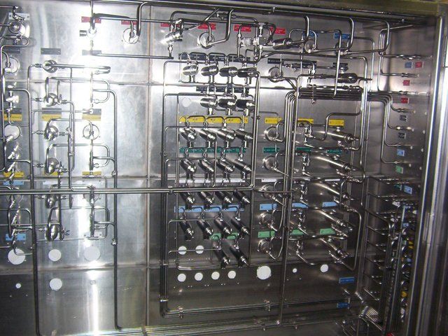A stainless steel wall with lots of pipes and valves