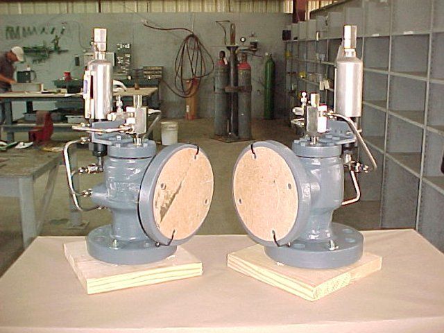 Two valves are sitting on a table in a factory.