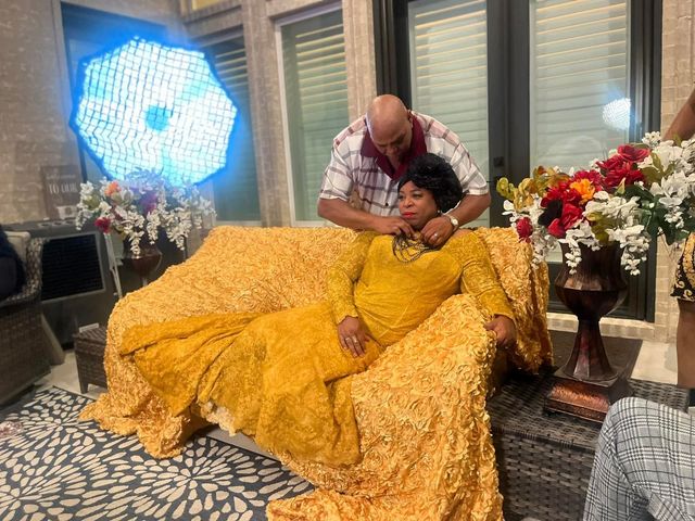 Man adjusting the necklace of a person in a yellow dress seated on a golden couch. Bright light in background.