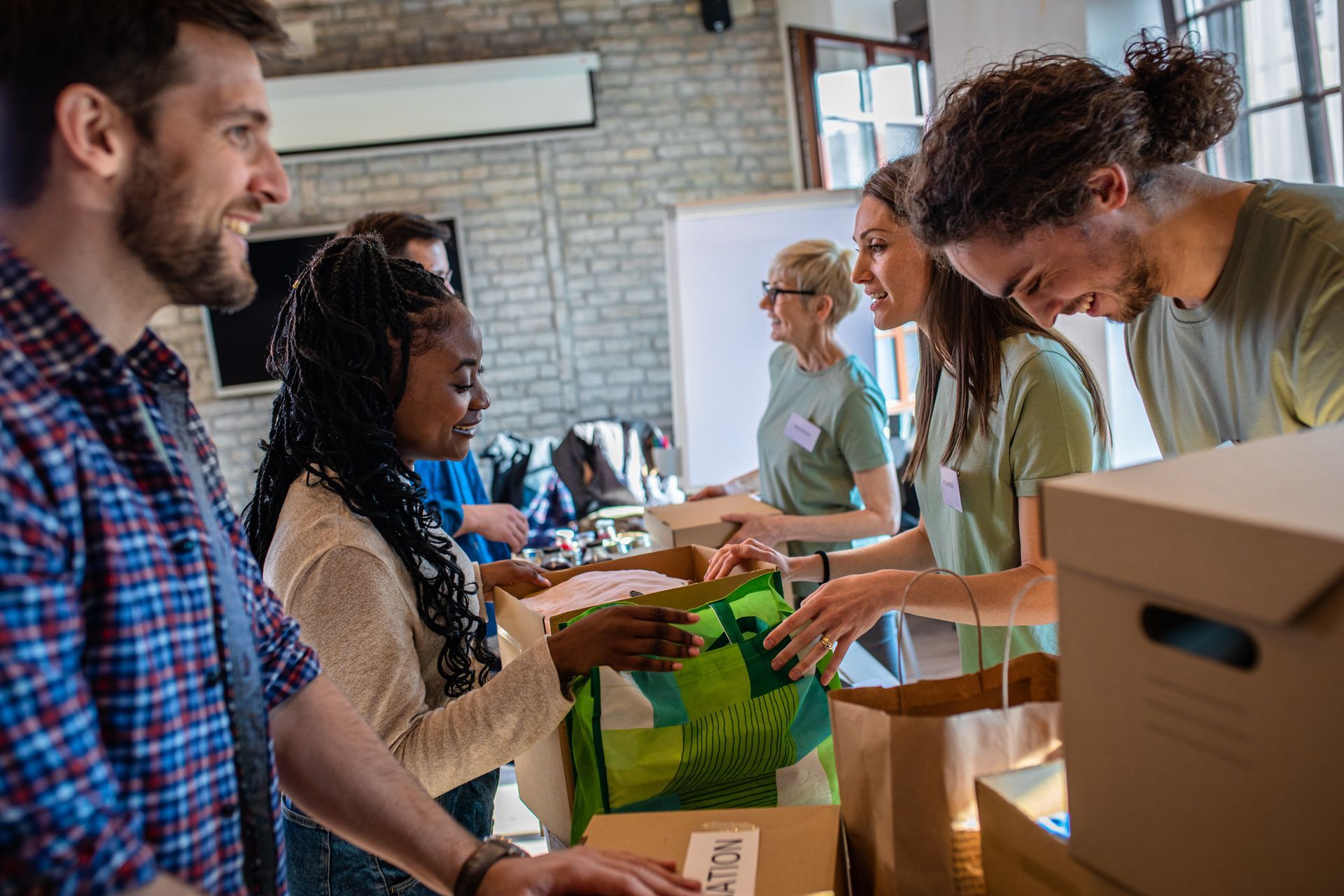 A group of people are standing around a table with boxes and bags.