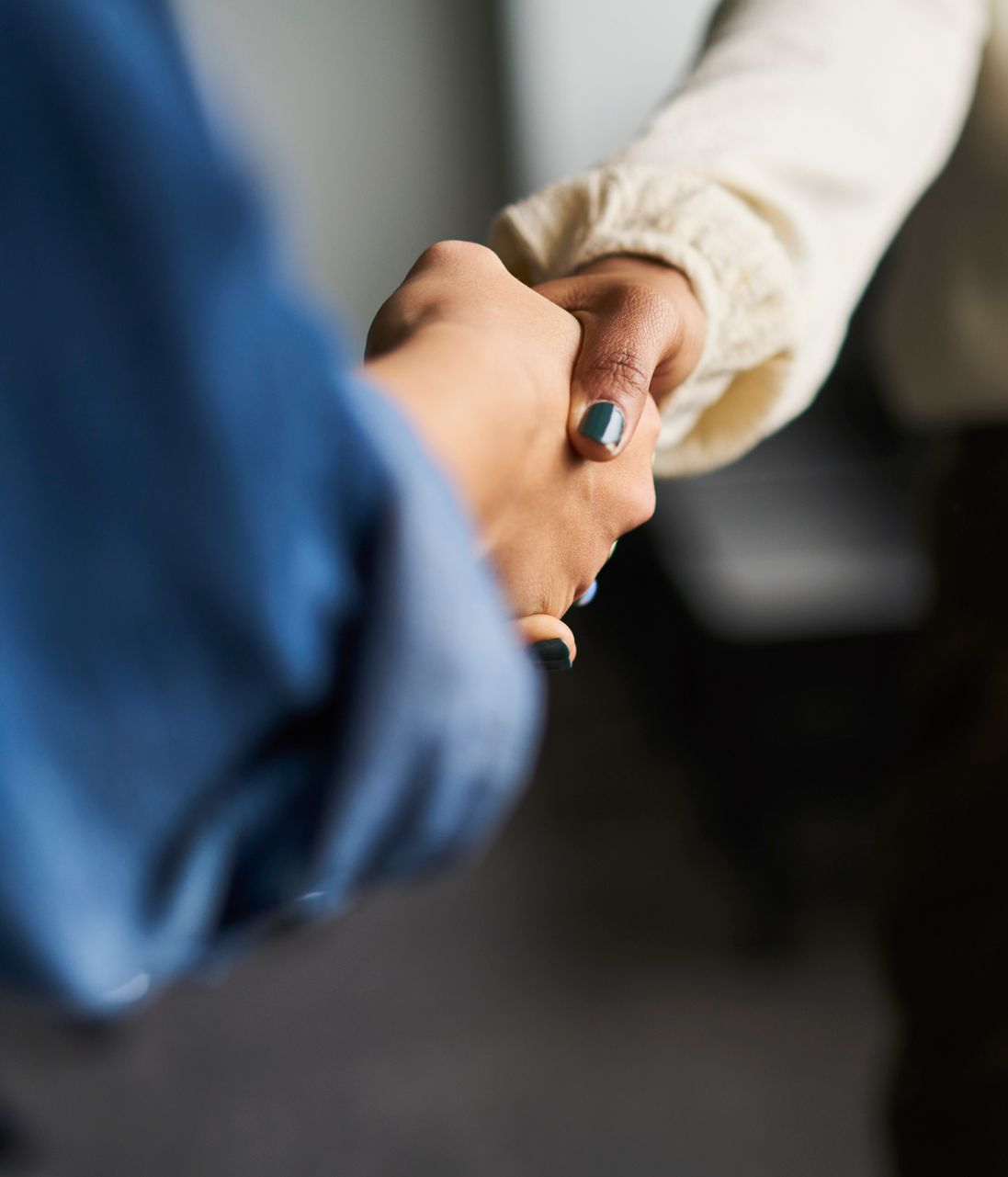 Man and woman shaking hands with an advisor at a desk. Smiling, indoors.