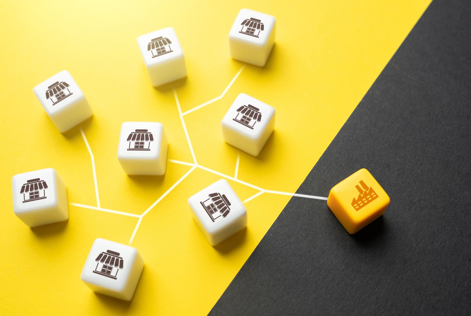 White cubes with store icons connected to a factory cube on a yellow and black background.