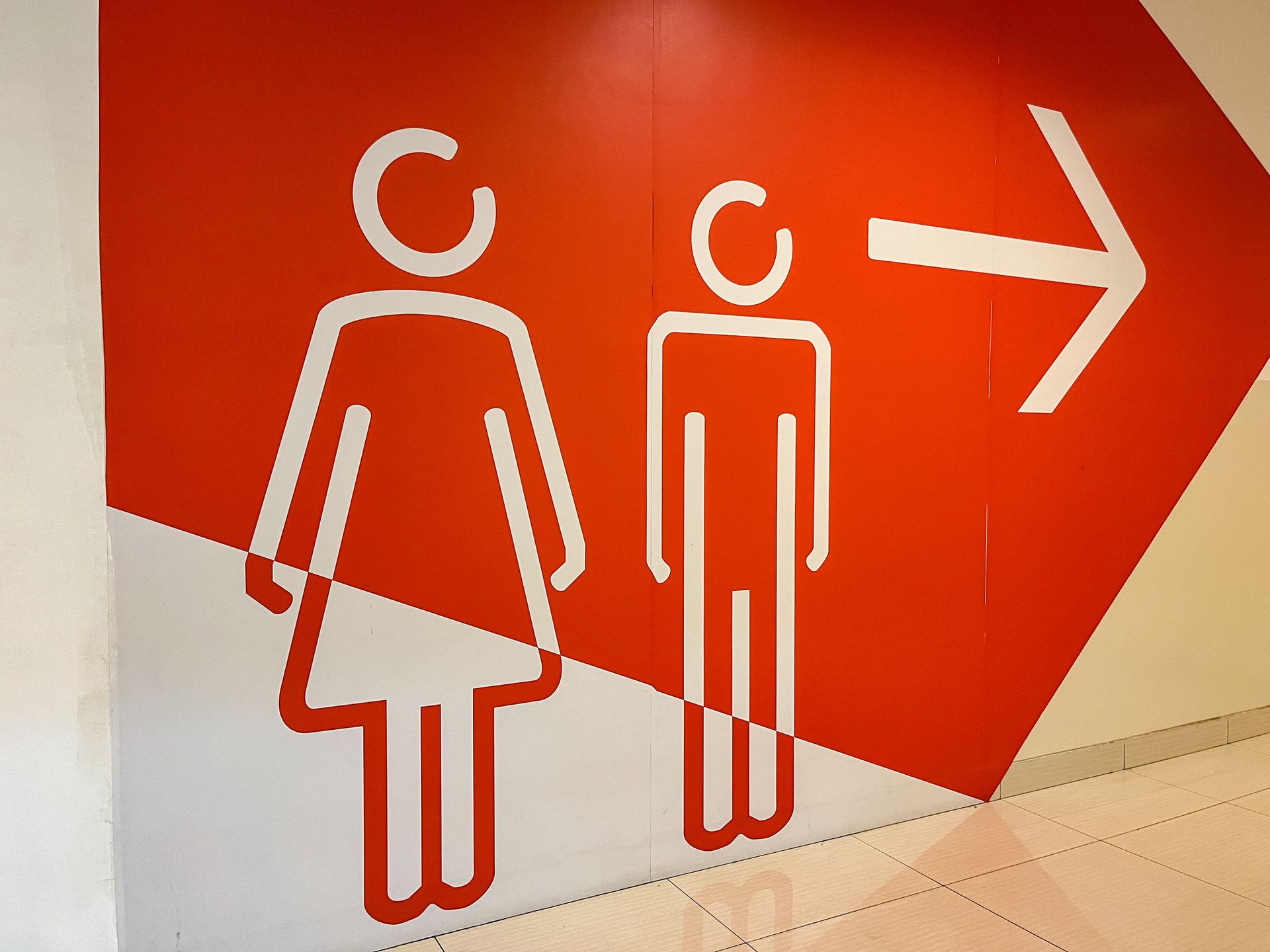 Wall print with restroom icons and a right-pointing arrow for directional guidance.