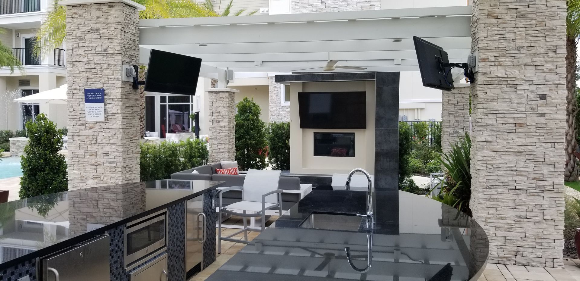 A large outdoor kitchen with a television on the wall.